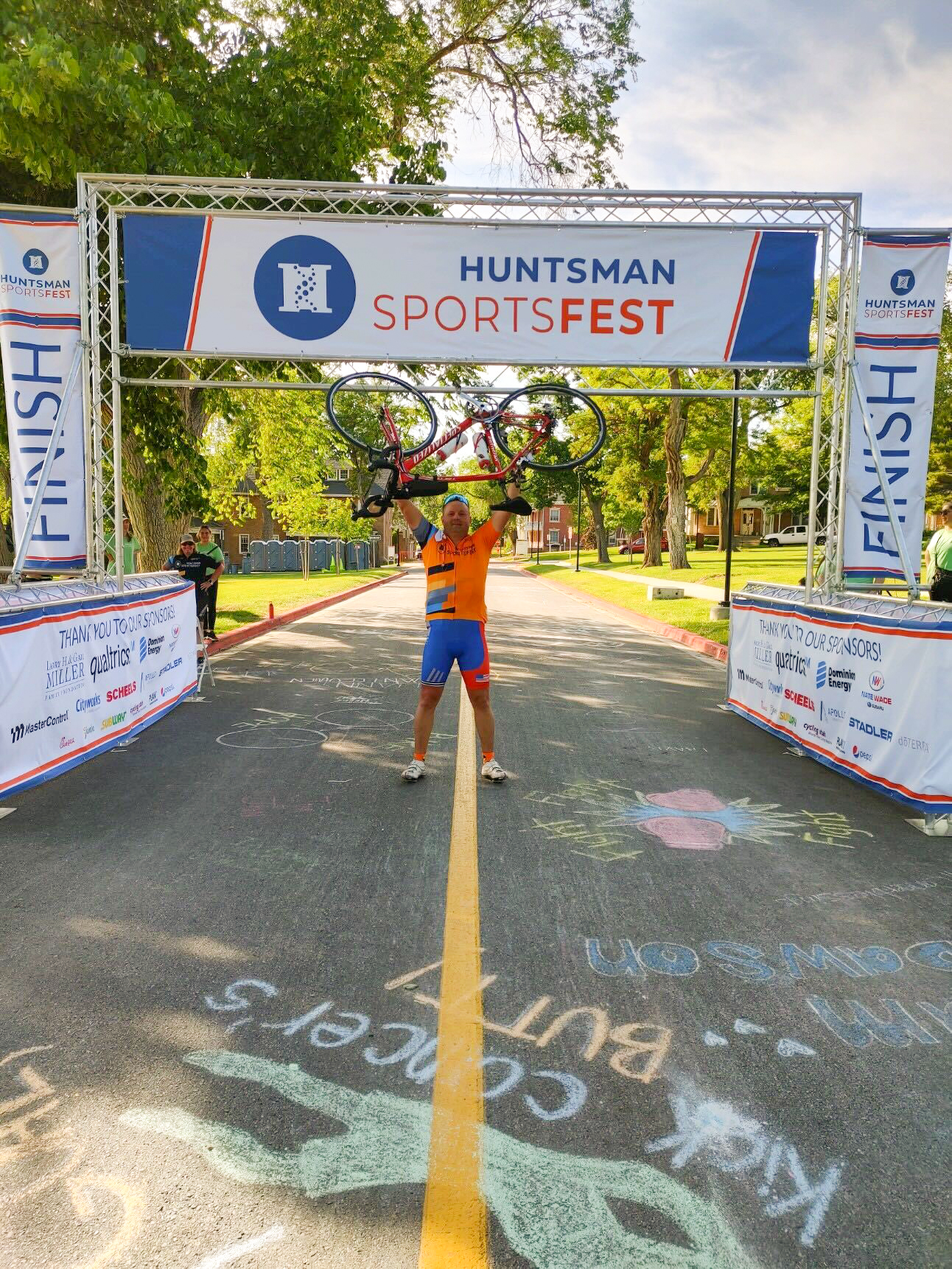 matt at finish line holding his bike over his head