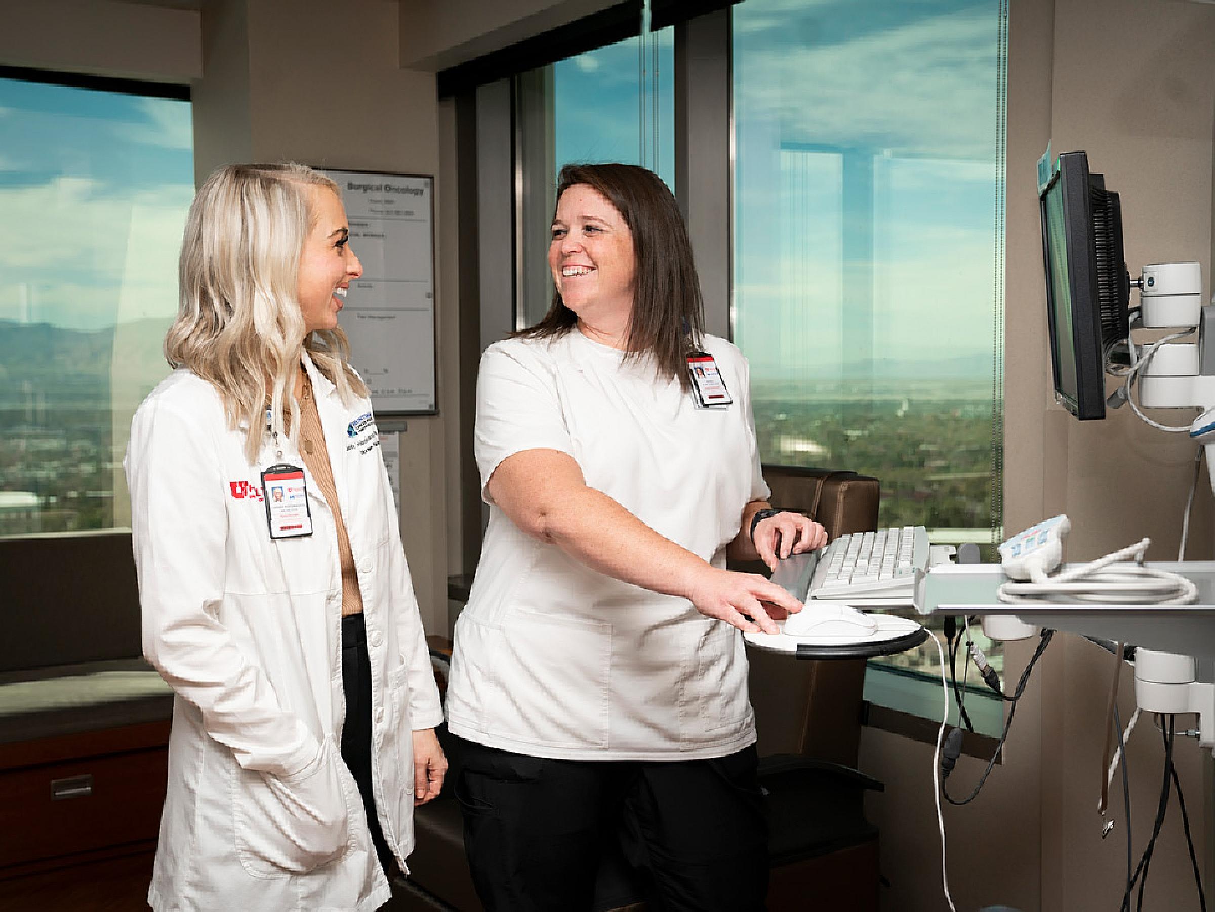 Two providers using computer and smiling as they talk