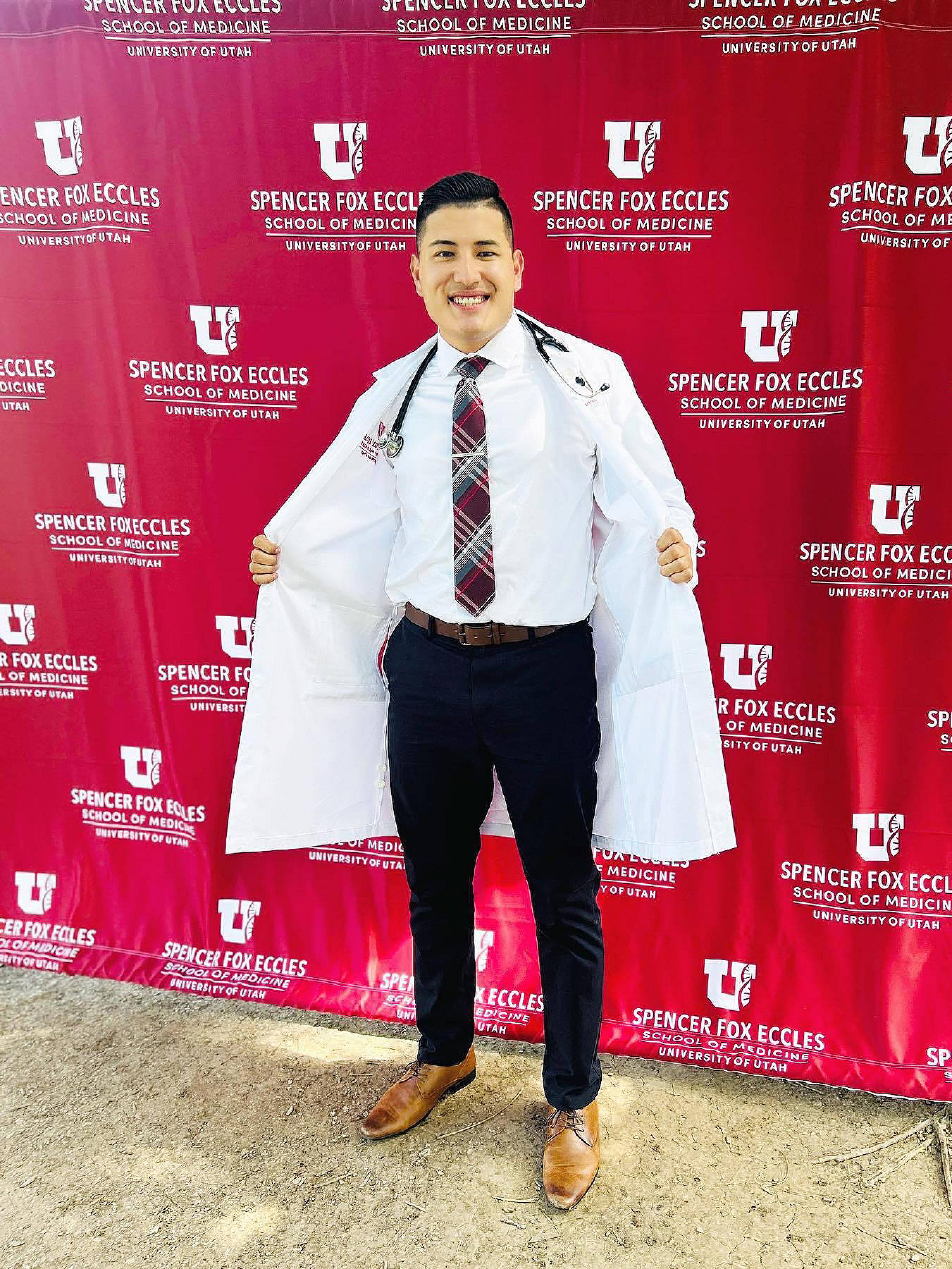 Adrian Portillo standing in front of a step and repeat backdrop at an event
