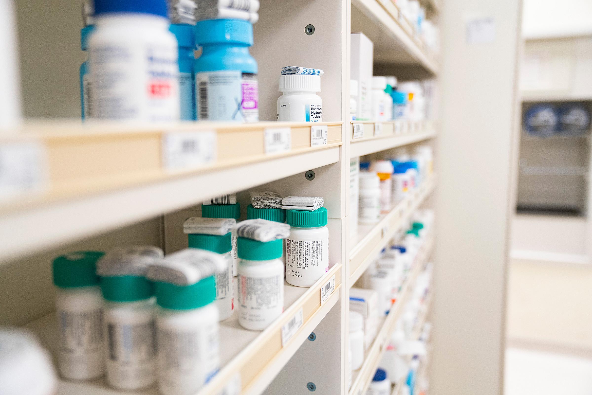 Rows of shelves filled with pill bottles in a pharmacy