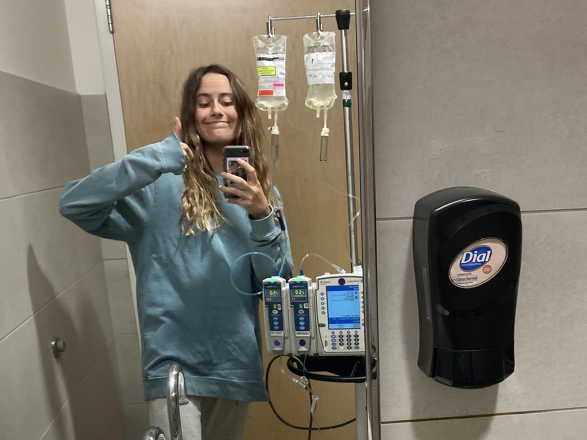 Brinlee Luster taking a selfie with her IV bags in the bathroom mirror