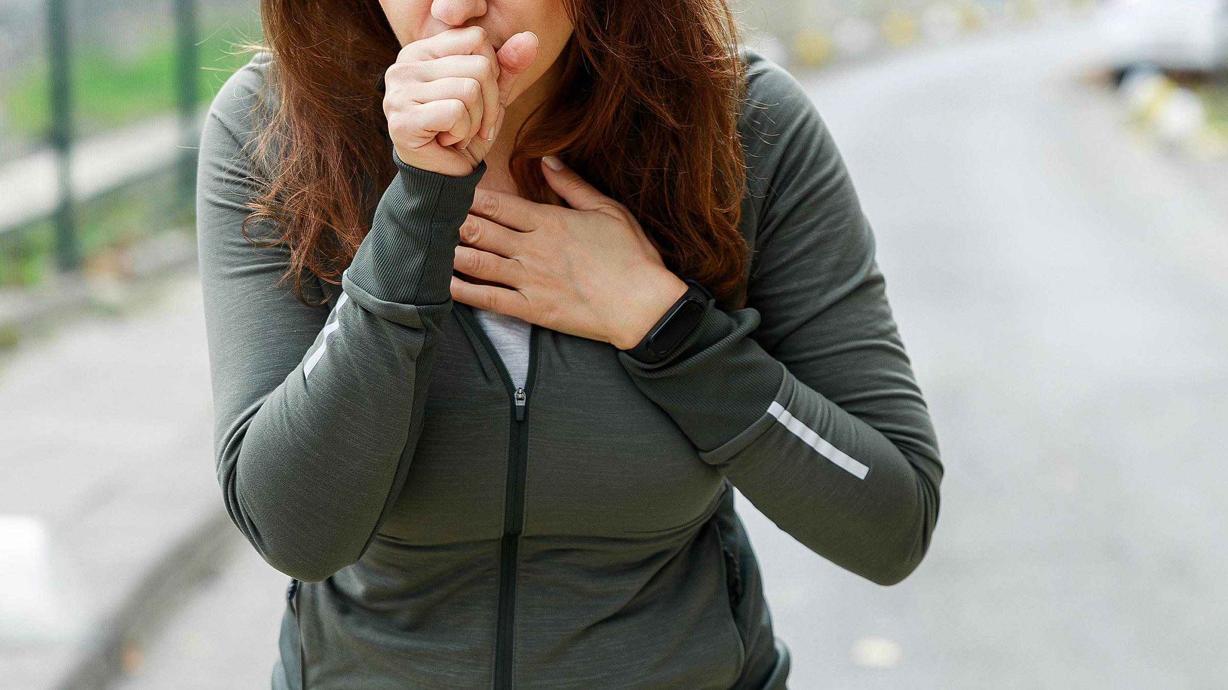 Woman coughing and pressing a hand to her chest