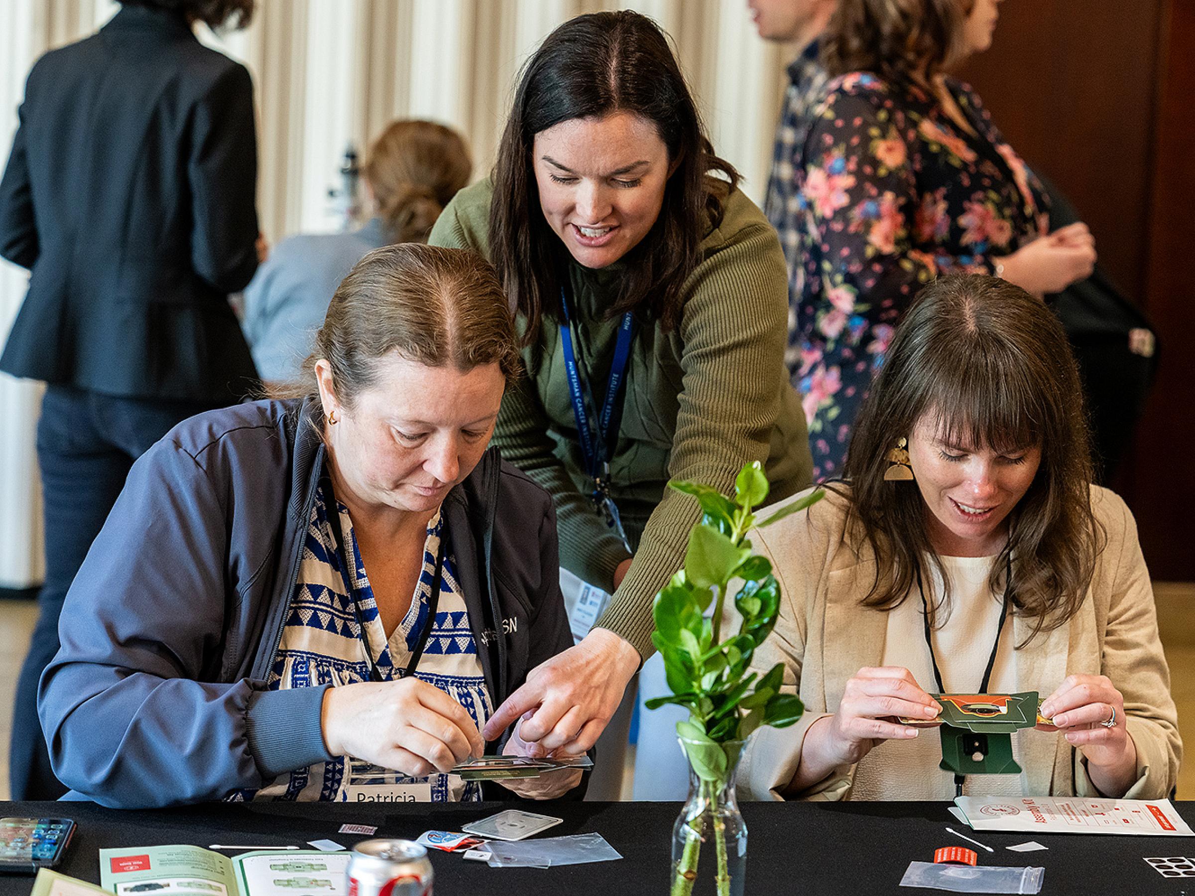 Mary Playdon helping participants make foldable microscopes