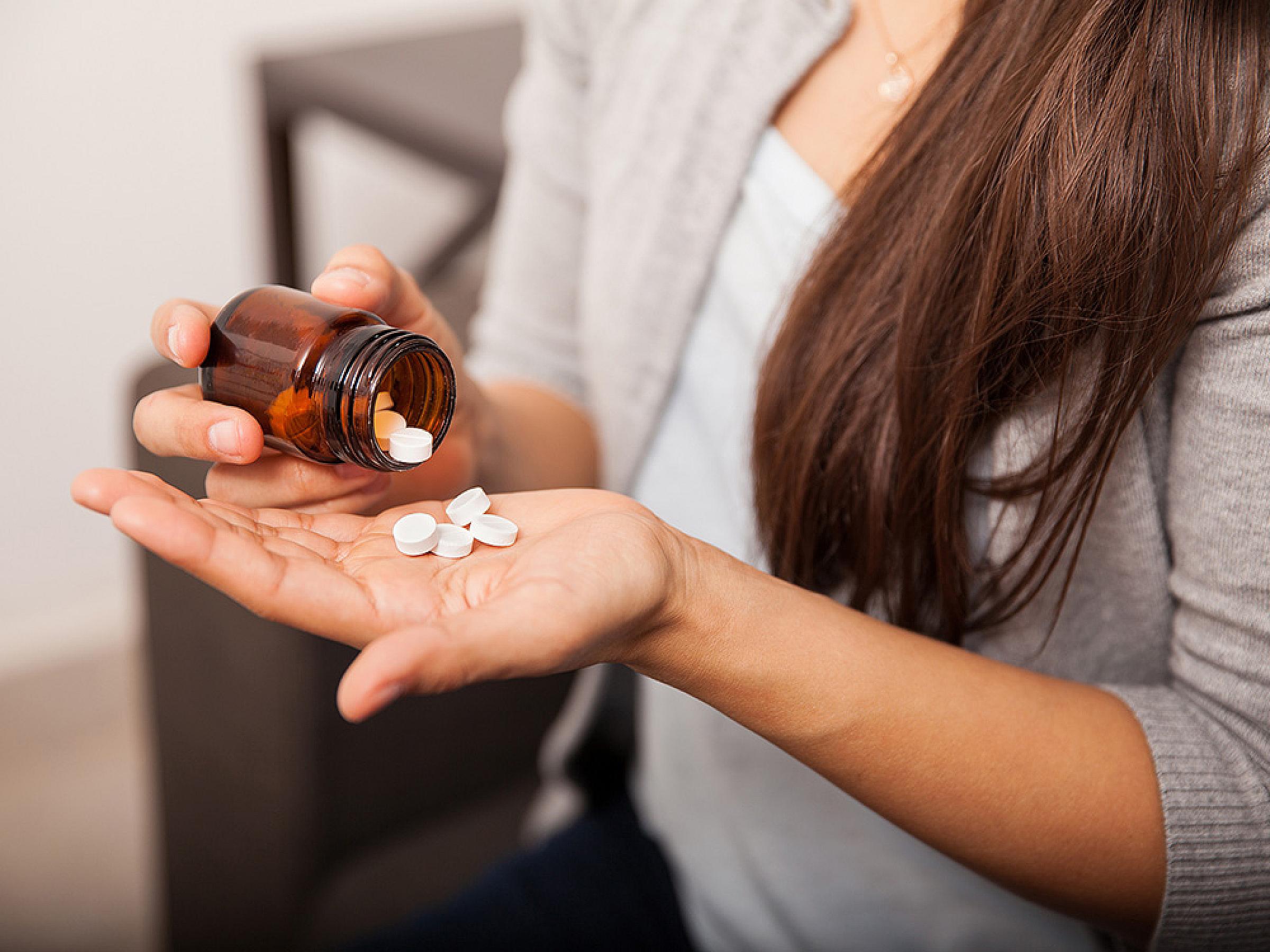 Woman holding a pile of aspirin in her hand