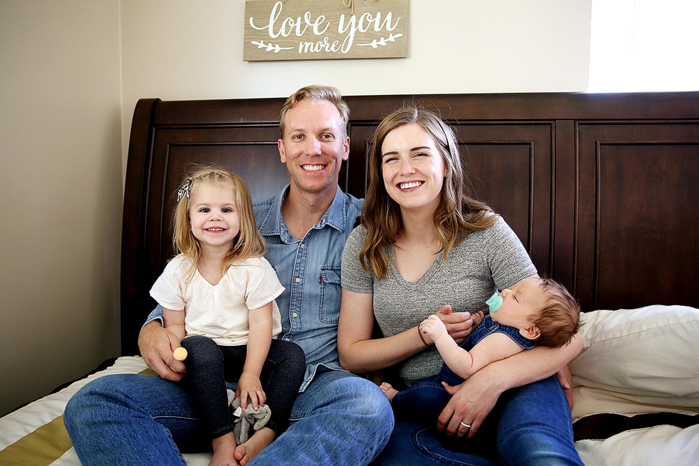 Trey Thompson with his wife and two children sitting on a bed