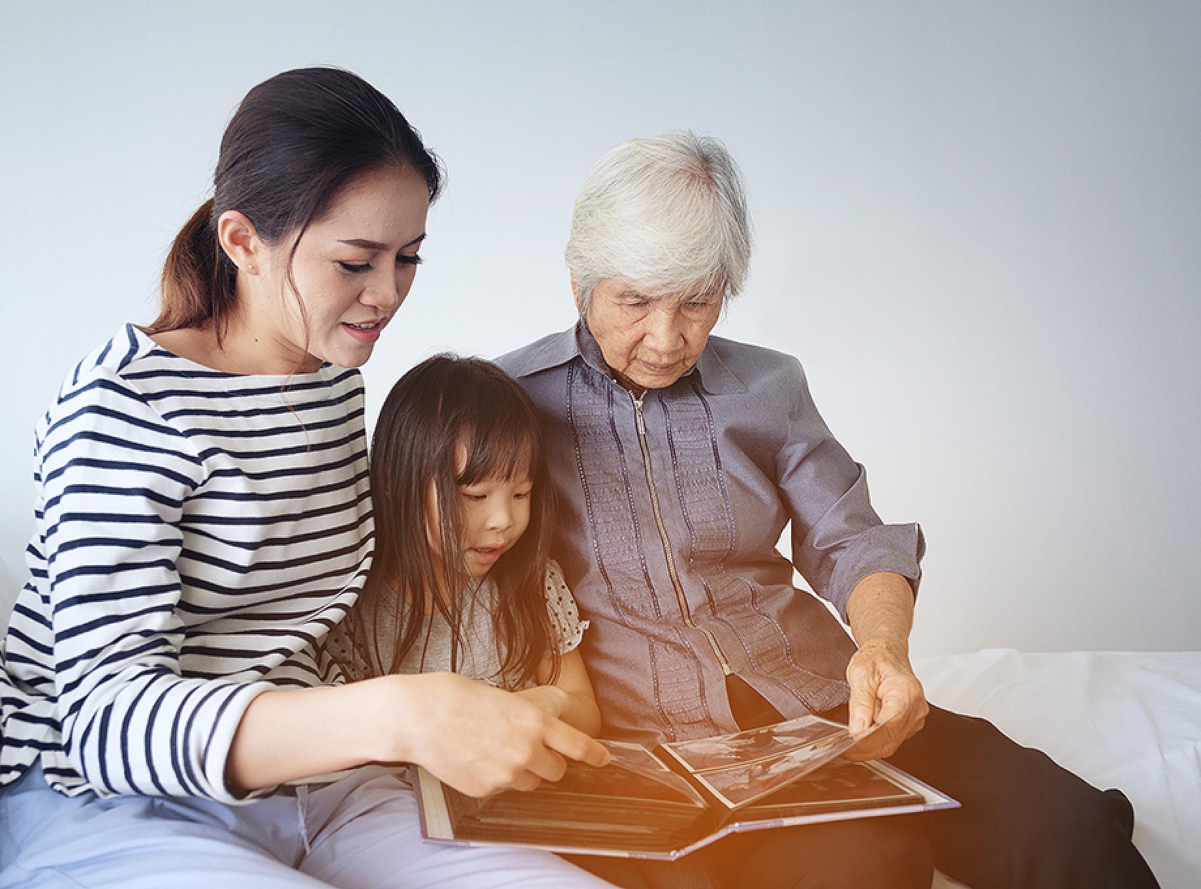 Mother, Daughter, and Grandmother Sitting Together Viewing Photo Album