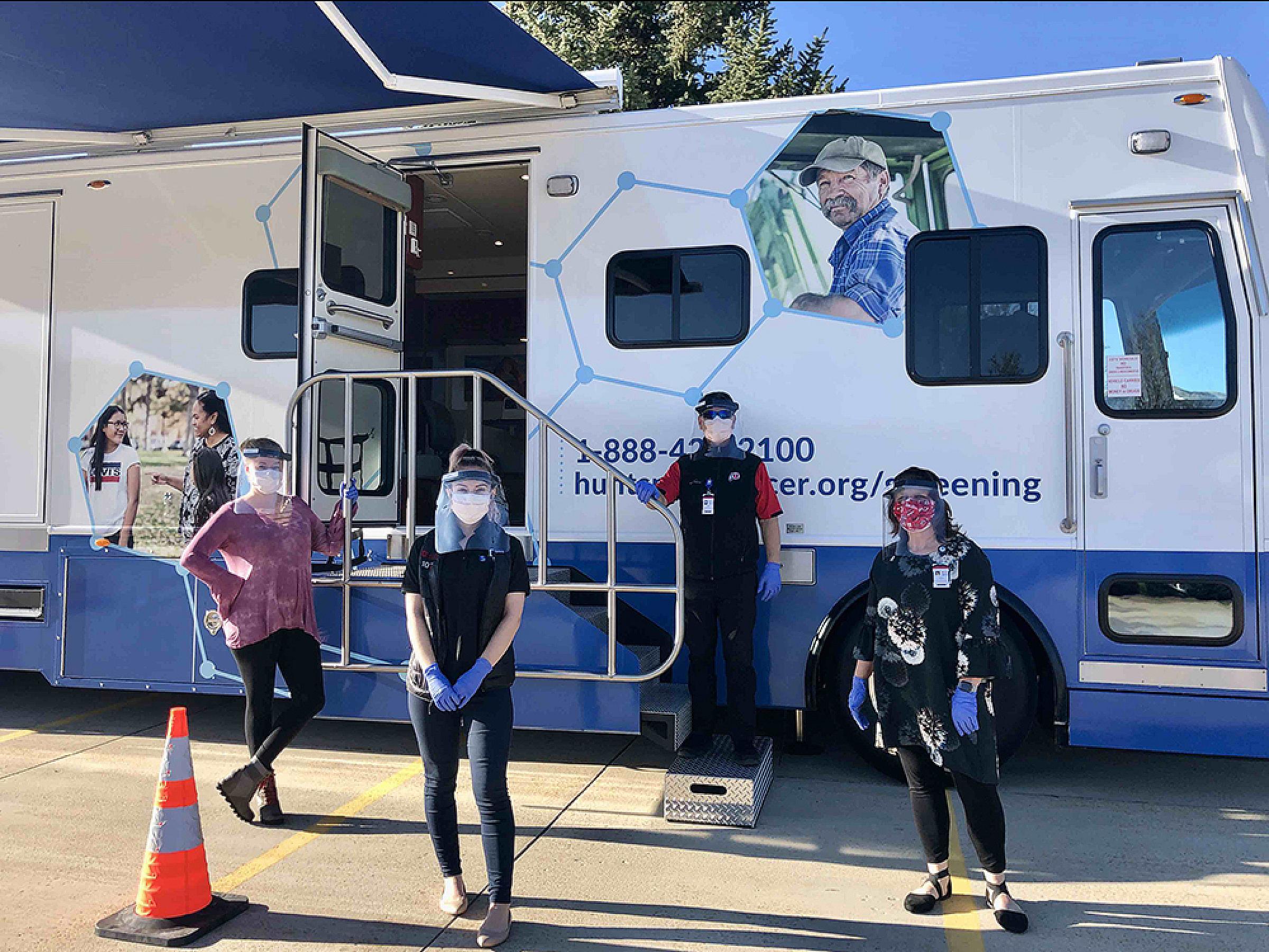 Staff members standing with Cancer Education and Screening Bus