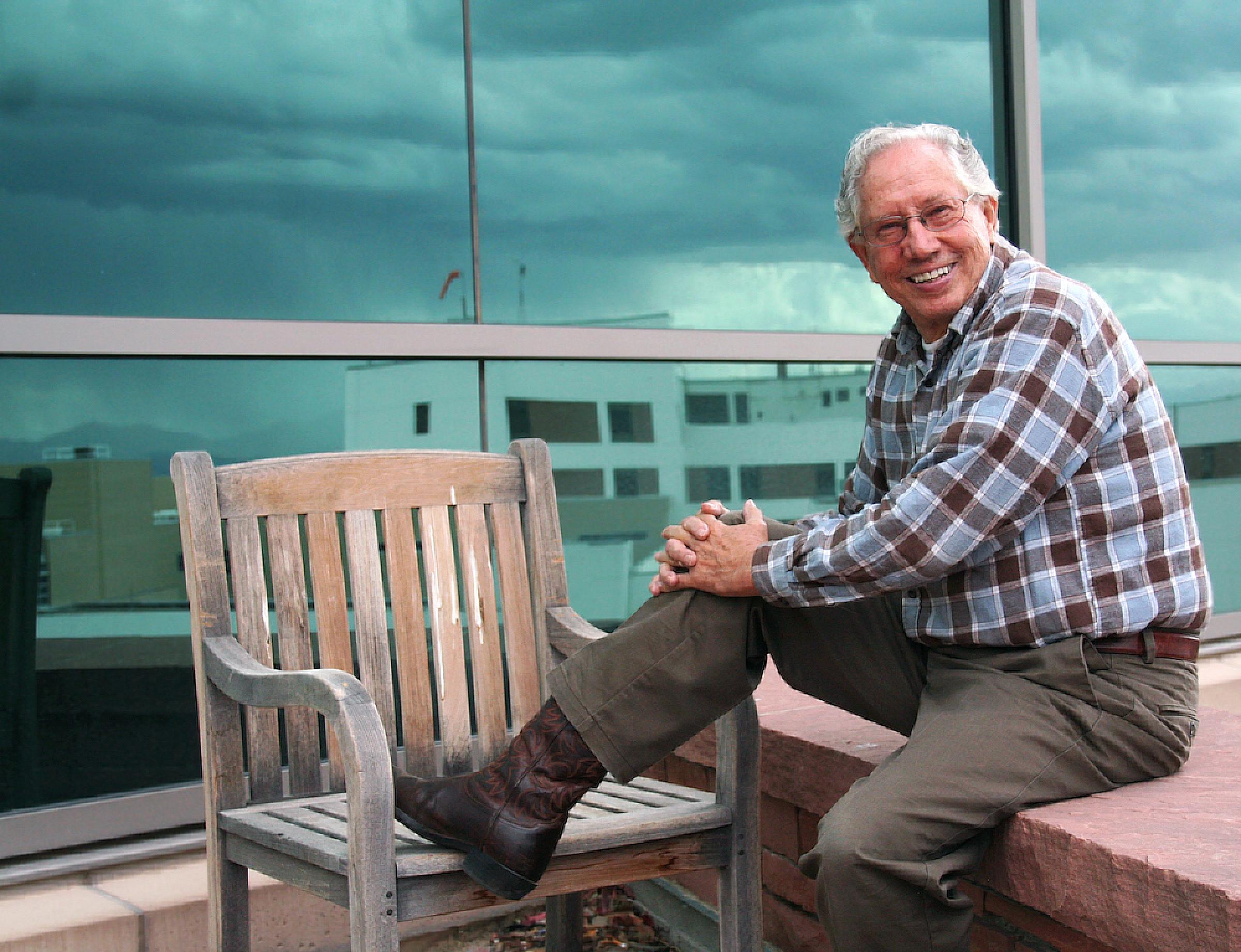 Monte Bona sitting on the patient patio at Huntsman Cancer Institute with one boot up on a chair