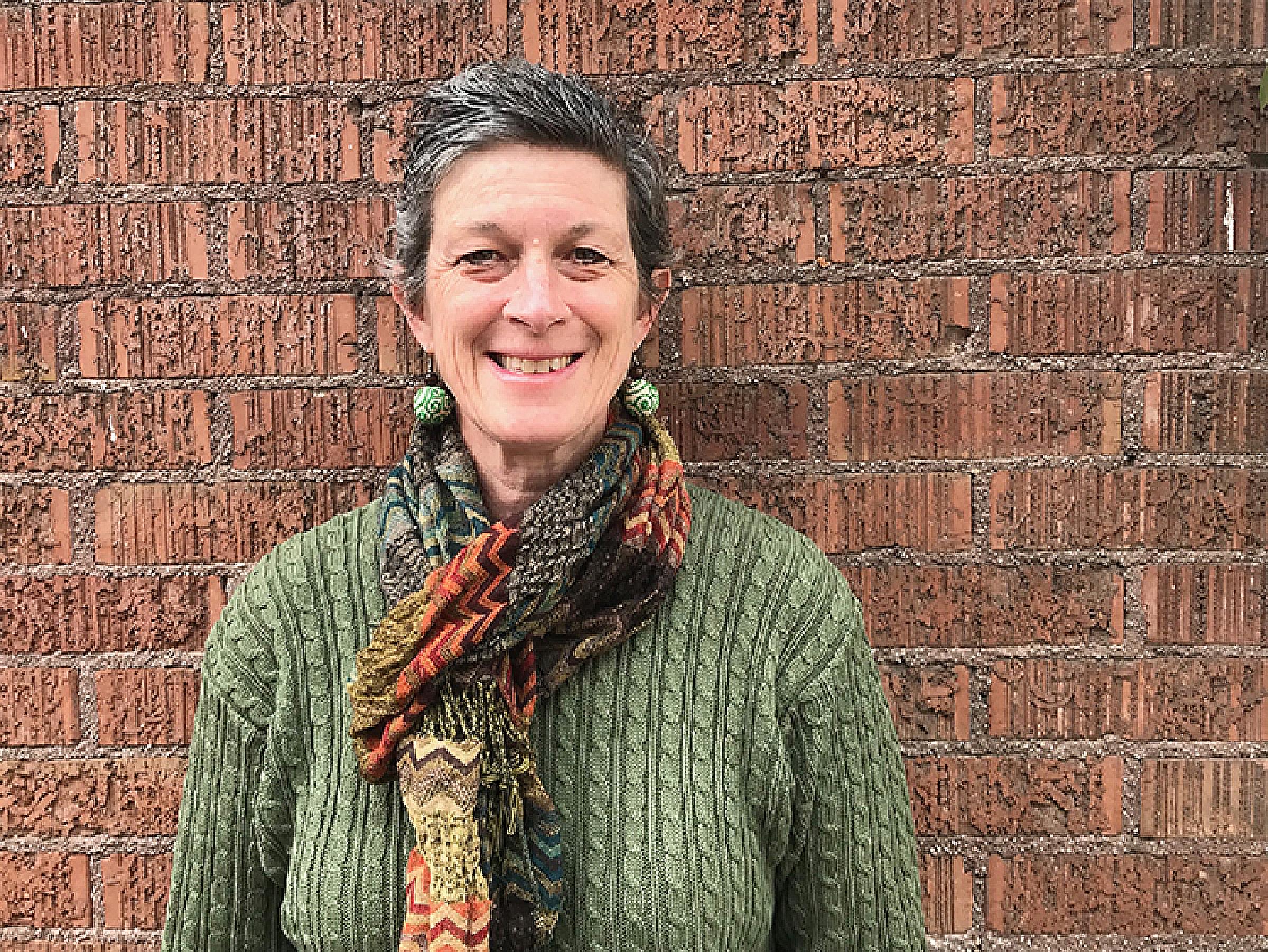 woman wearing green top and scarf against brick wall