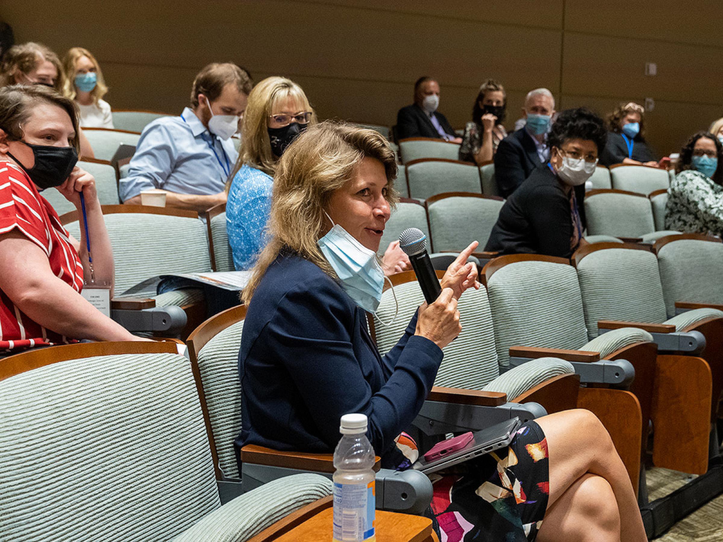 Neli Ulrich sitting in auditorium speaking
