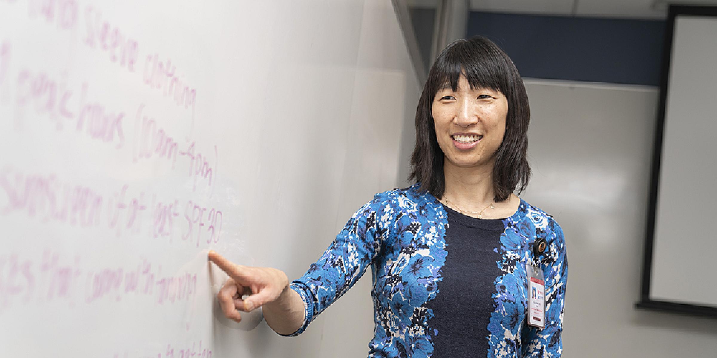 Yelena Wu next to dry erase board