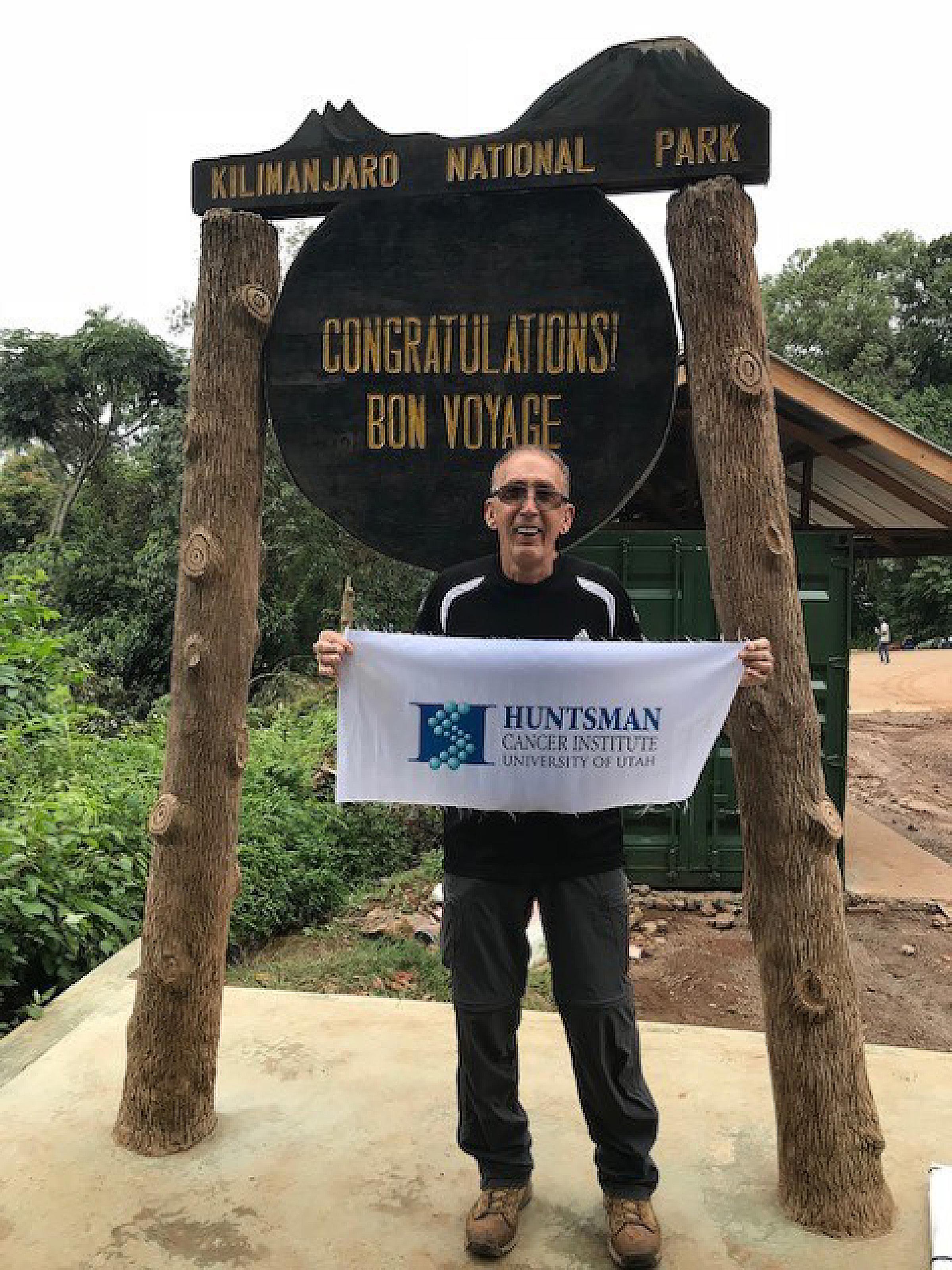 Kenneth Henderson at Kilimanjaro holding an HCI banner