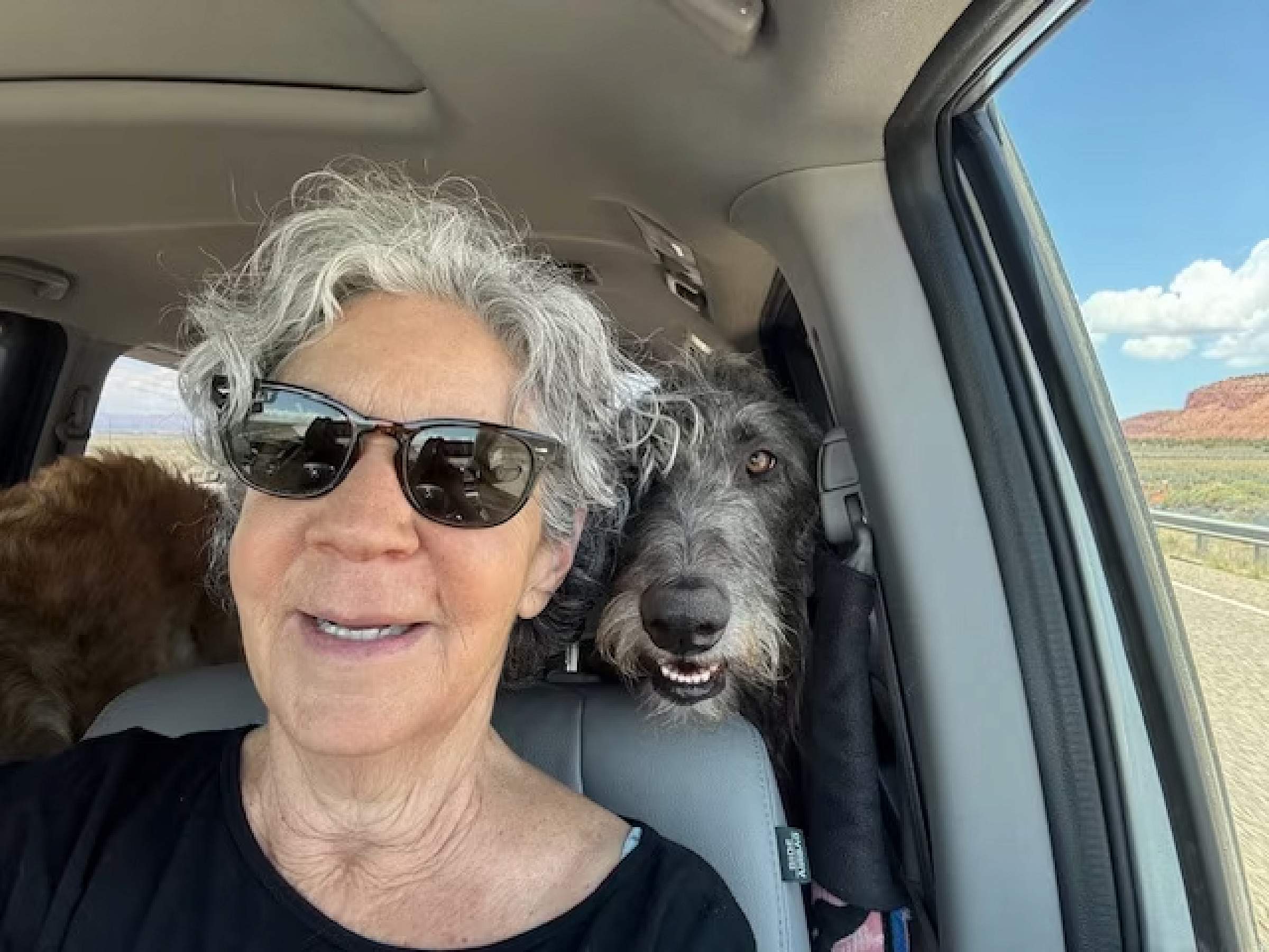 Claudia Presto in a car with a dog in the seat behind her