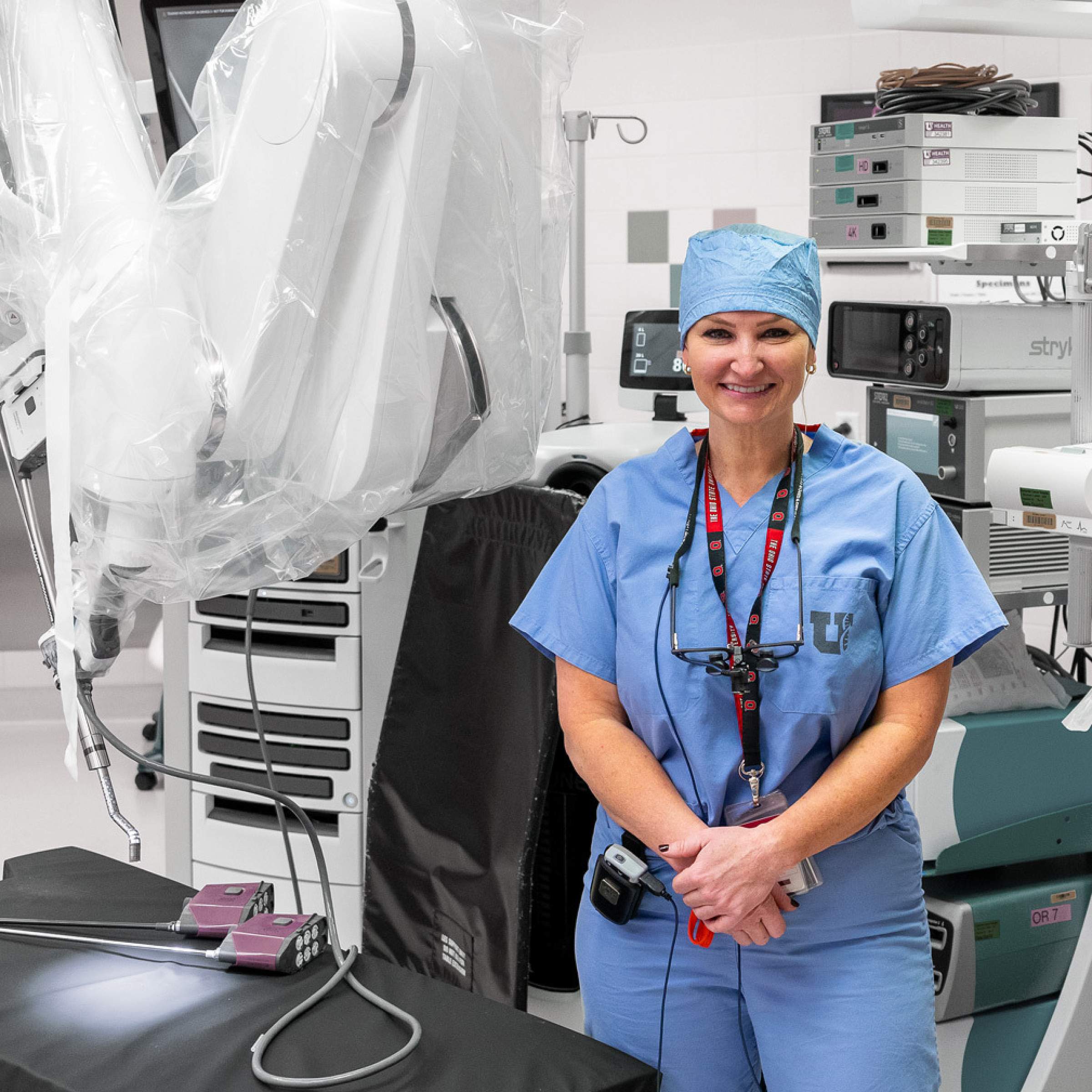 Hilary McCrary stands in front of robotic surgery equipment,
