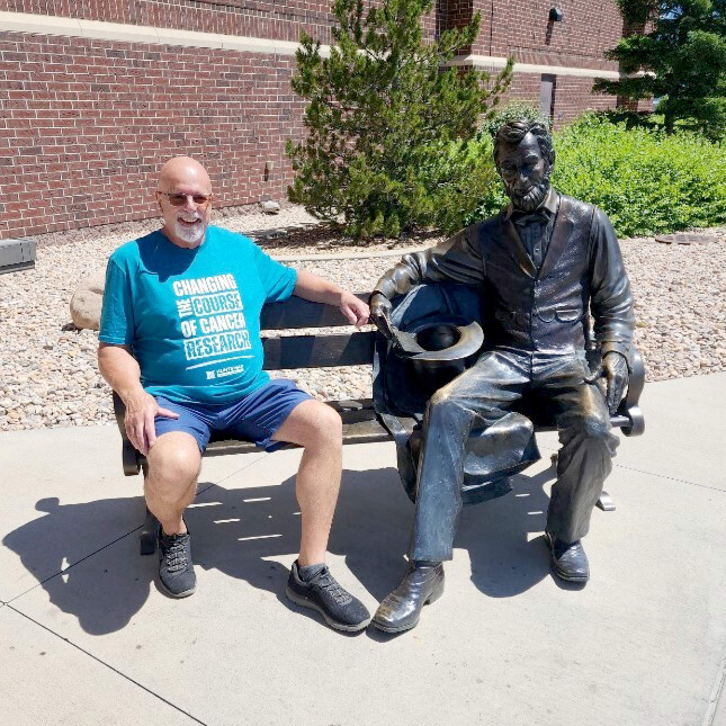 Jerry Barber sitting on a bench next to a statue of Abraham Lincoln
