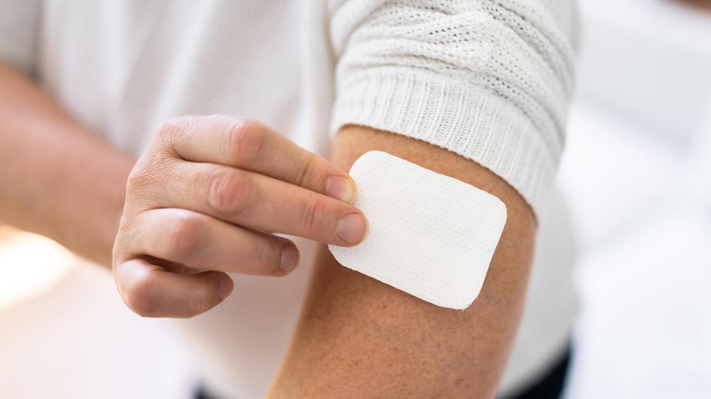 Woman putting HRT patch on her arm