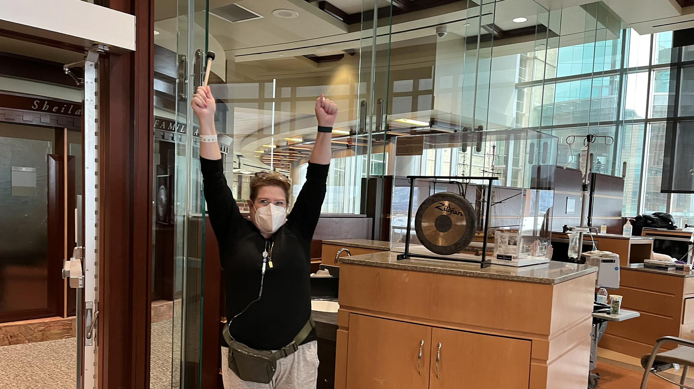 Noelle Gatlin banging a small gong to symbolize the end of her chemotherapy treatment