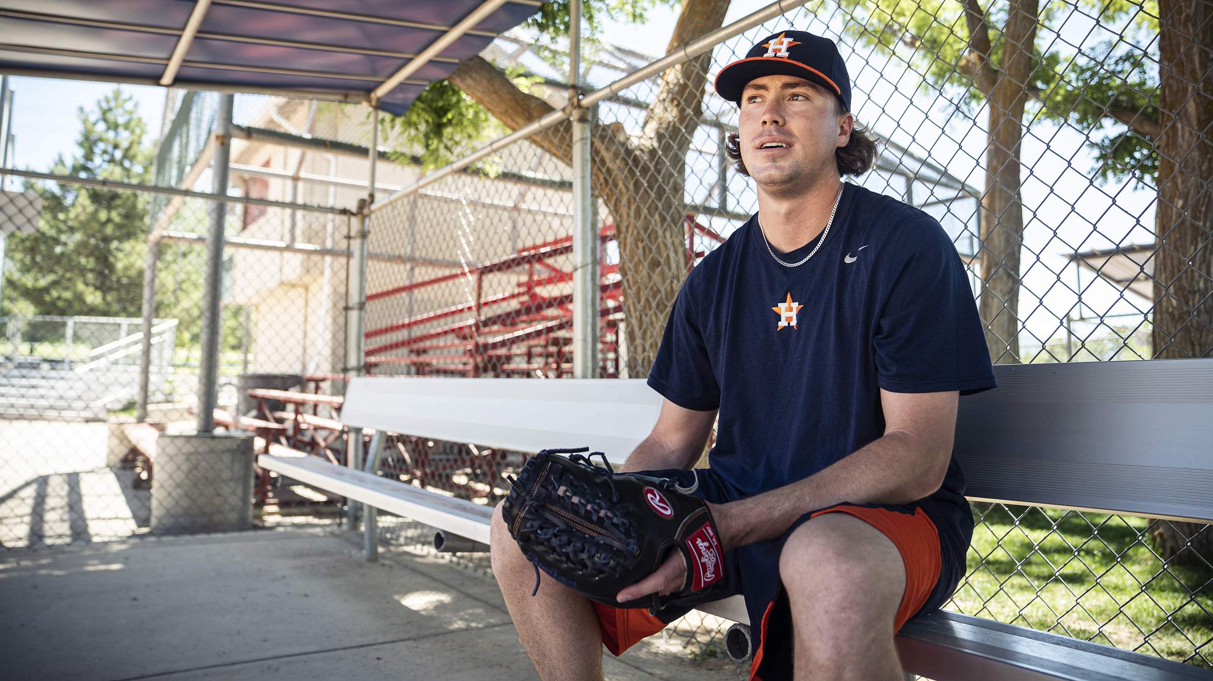 Adam Whitt sits on a bench with a baseball mitt