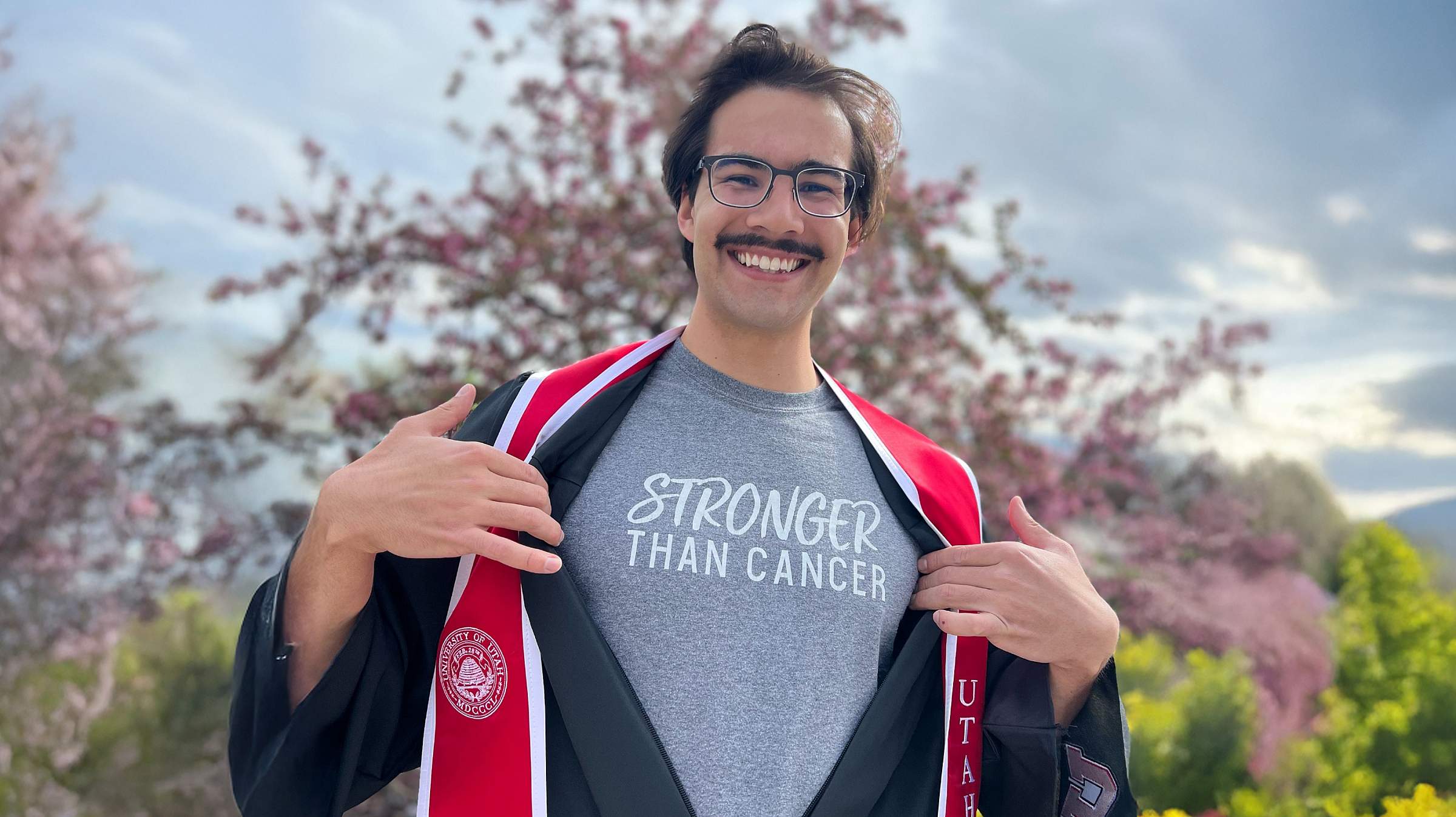 Anthony Bradley showing the t-shirt under his graduation gown and sash that reads "Stronger than Cancer"