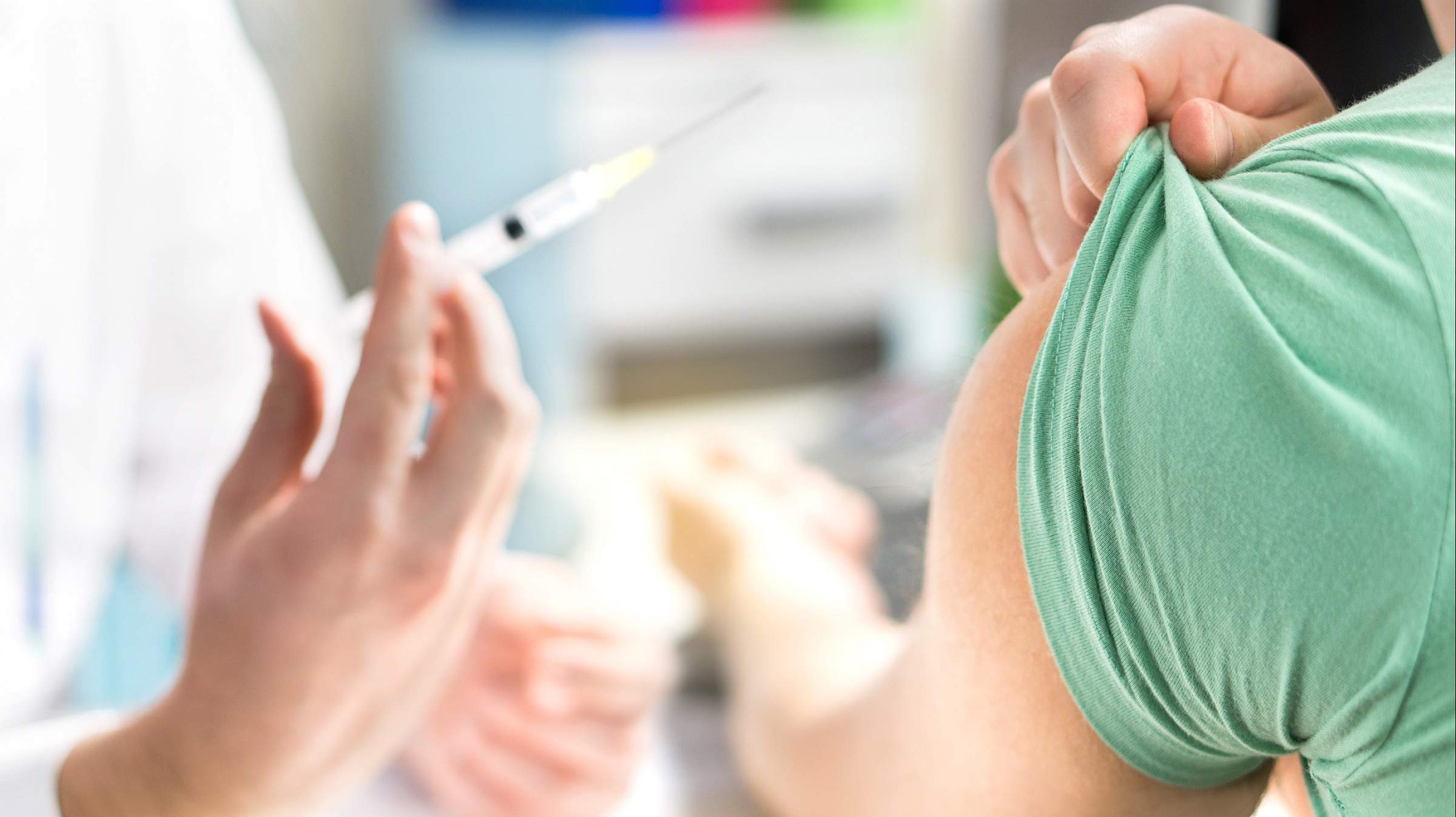Patient pulling up sleeve while a nurse holds up a syringe