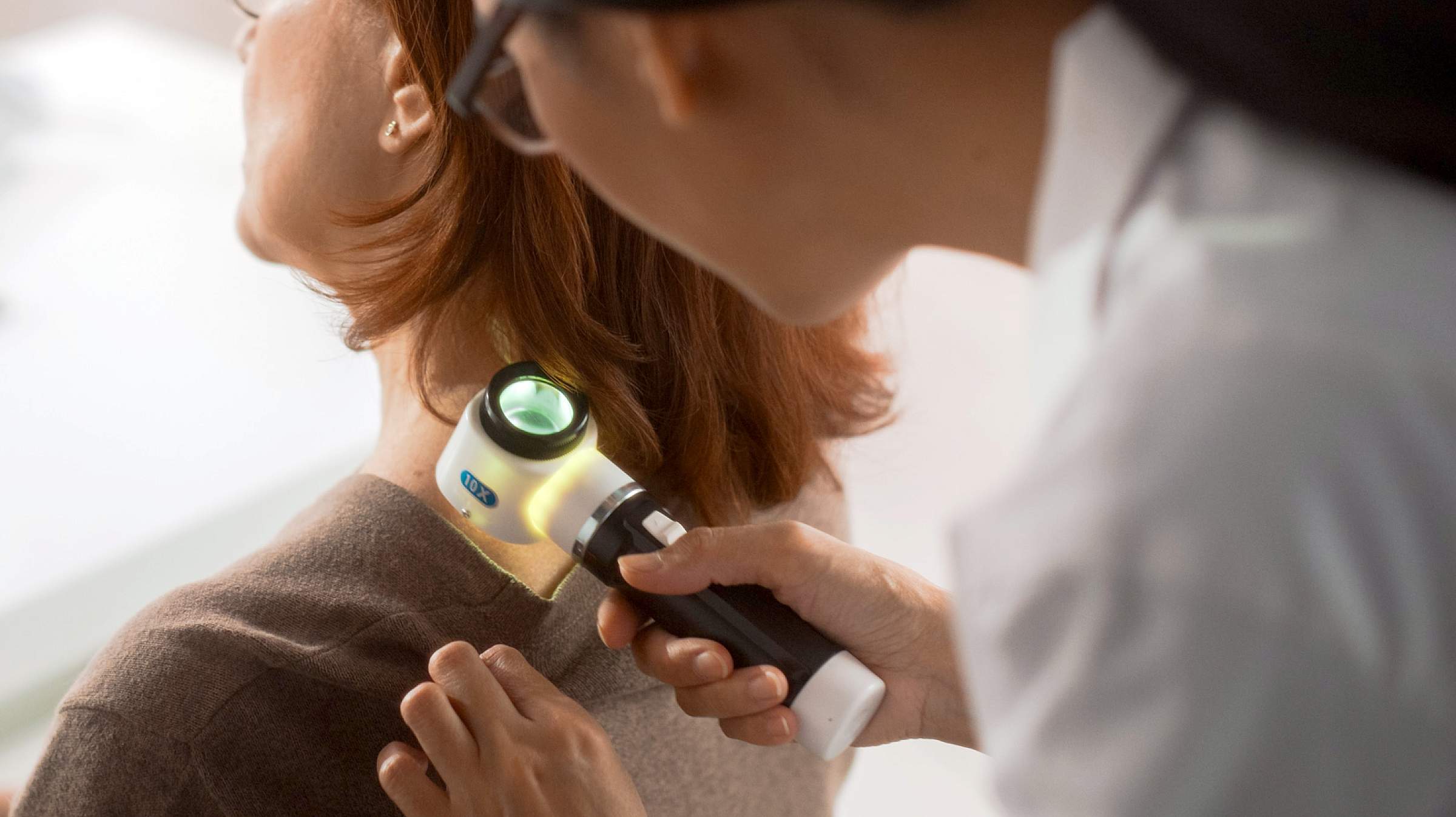Provider doing a skin check on the back of a women's neck