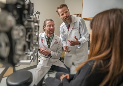 Vice Chair of Education, Jeff Pettey, MD, confers with resident Bradley Jacobsen, MD, left, and a patient.