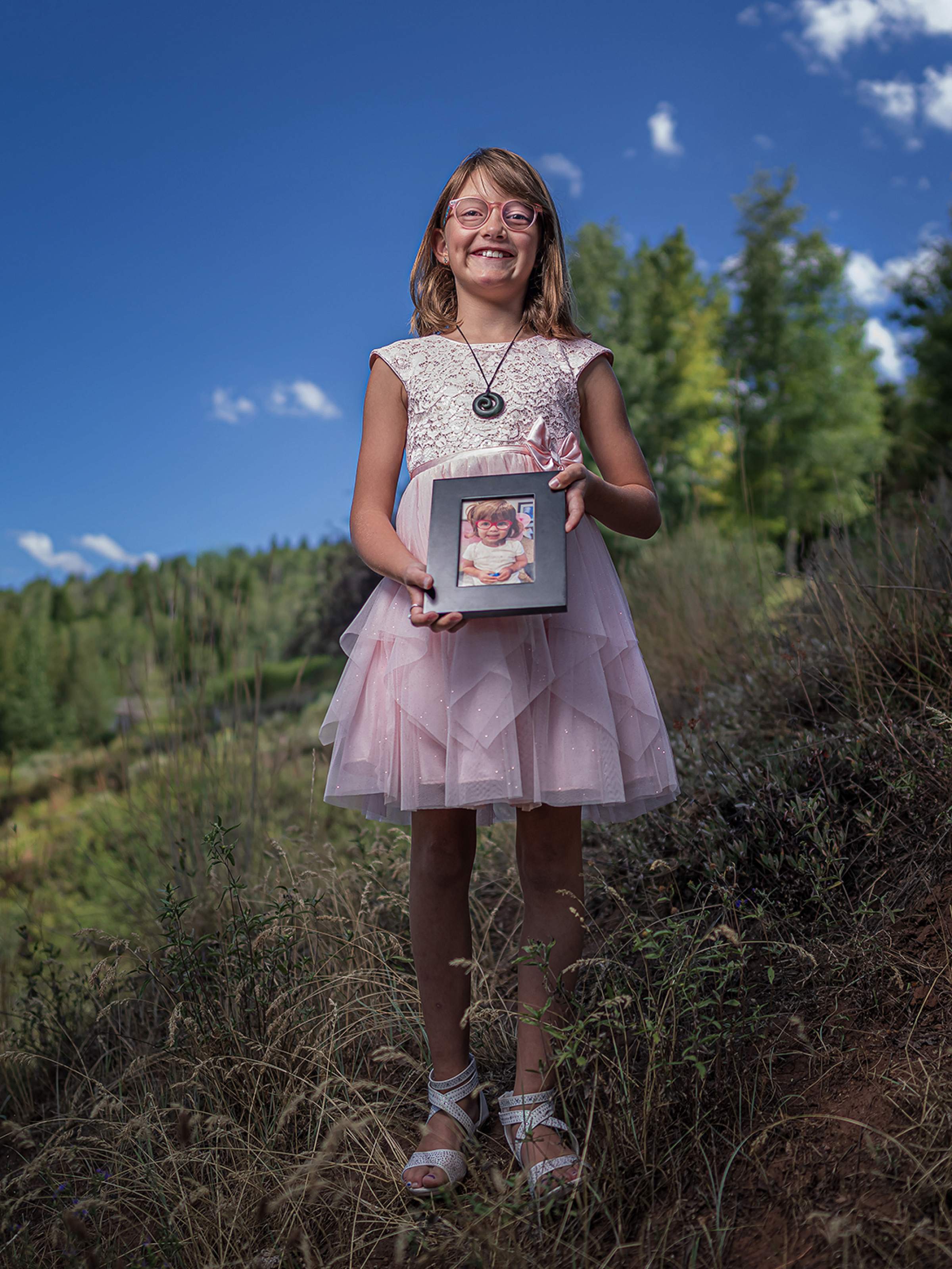 Wren holds a photo of an eyeglasses donor fund recipient.