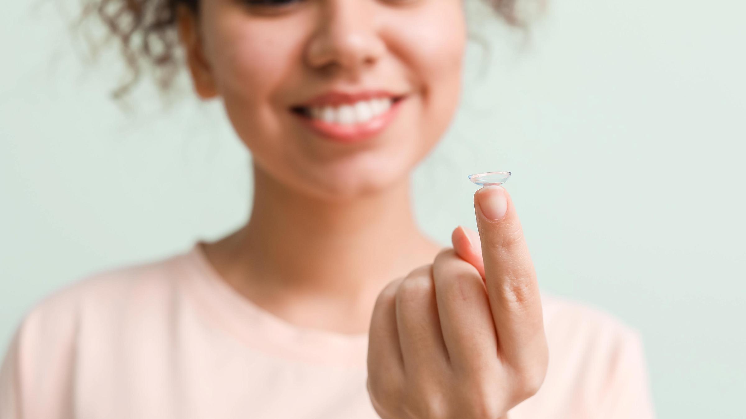 Woman holding a contact lens.