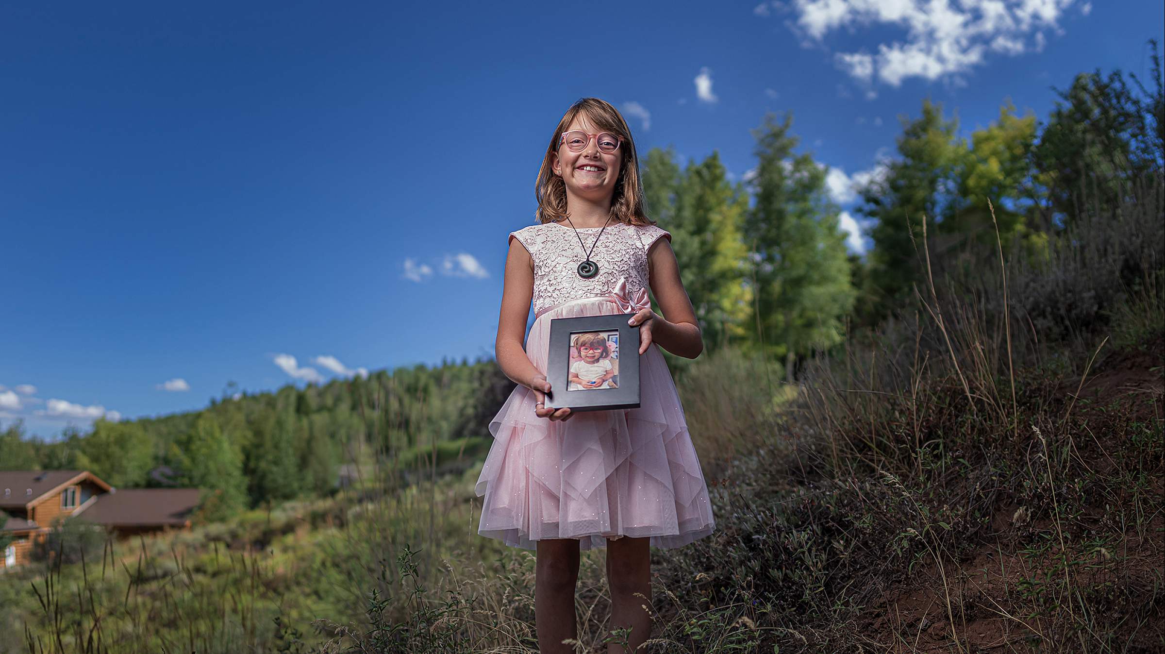 Wren holds a photo of an eyeglasses donor fund recipient.