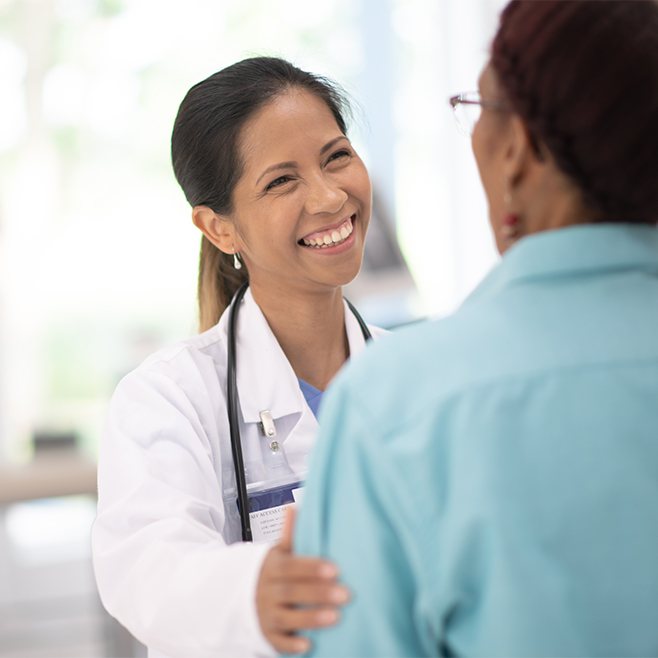 Brown-skinned female doctor smiling at older female patient