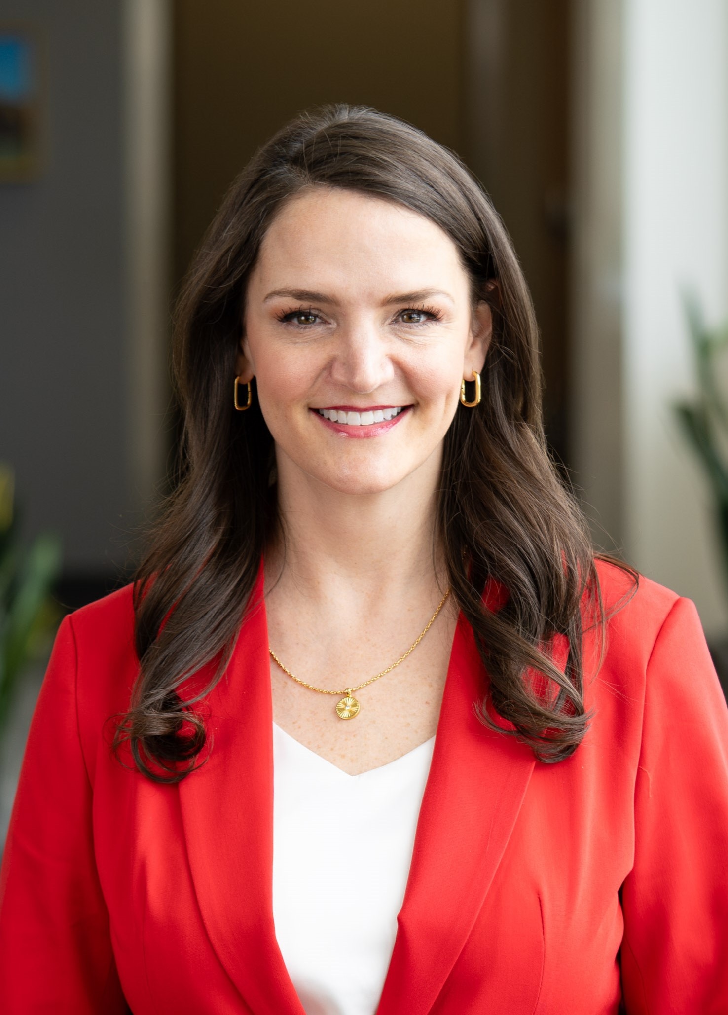 A person in a red blazer smiling at the camera.
