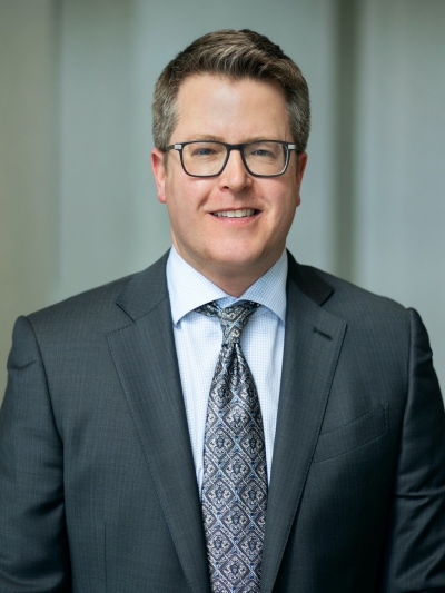 Profile photo of a person in a business suit and glasses
