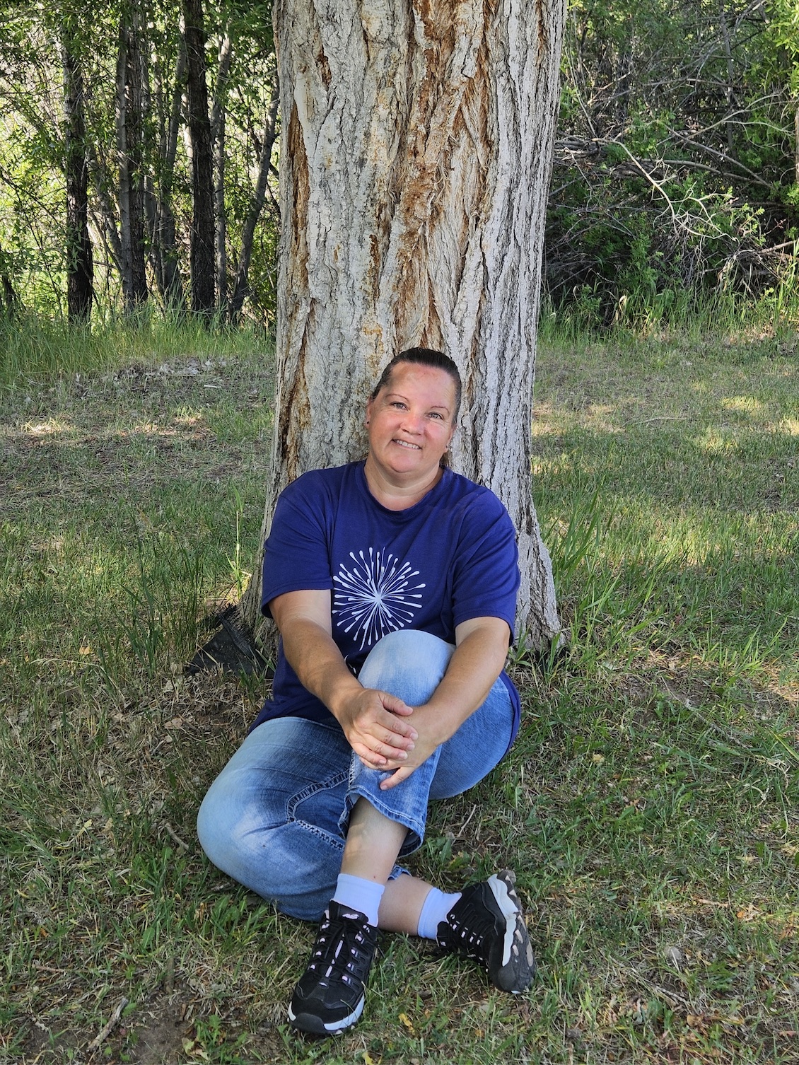 Jennifer Alvis sitting in front of a tree out enjoying nature