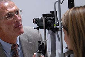 Male eye doctor checking female patient's eyes