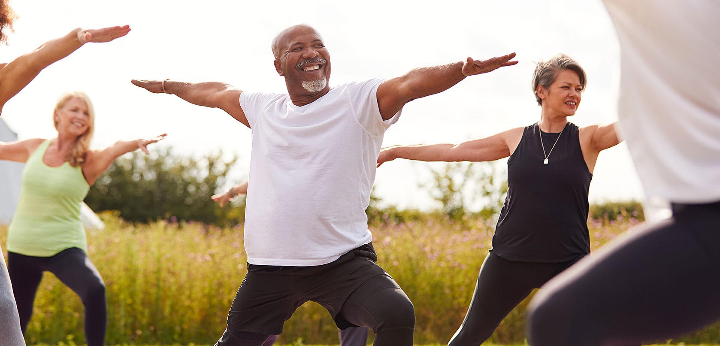 Older man and other individuals doing yoga stretches