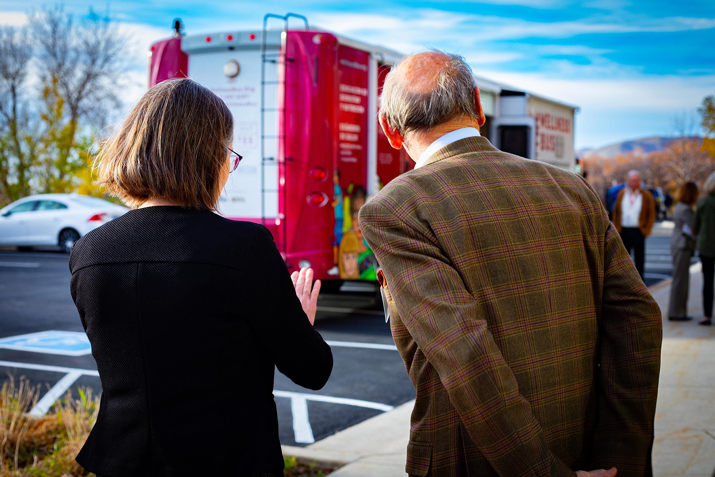 Amy B. Locke talks with Bernard Osher. Their backs are to the camera. 