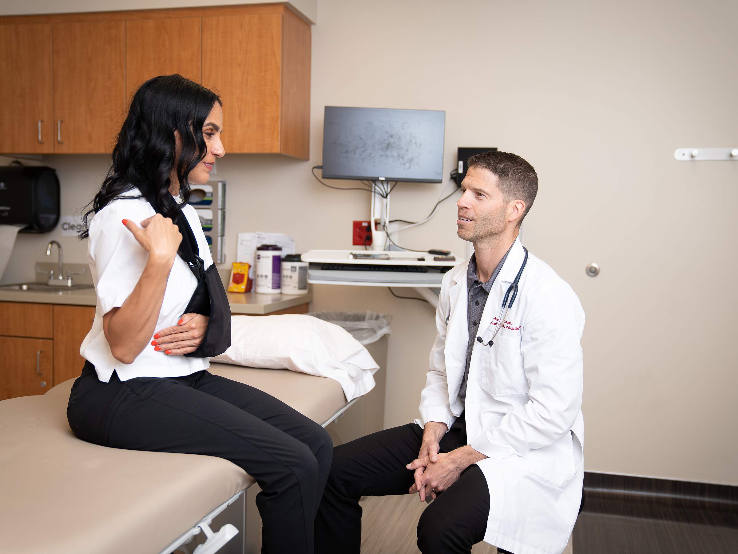 Aaron Provance, CAQSM, FAAP, MD, listens to a patient discuss her arm injury