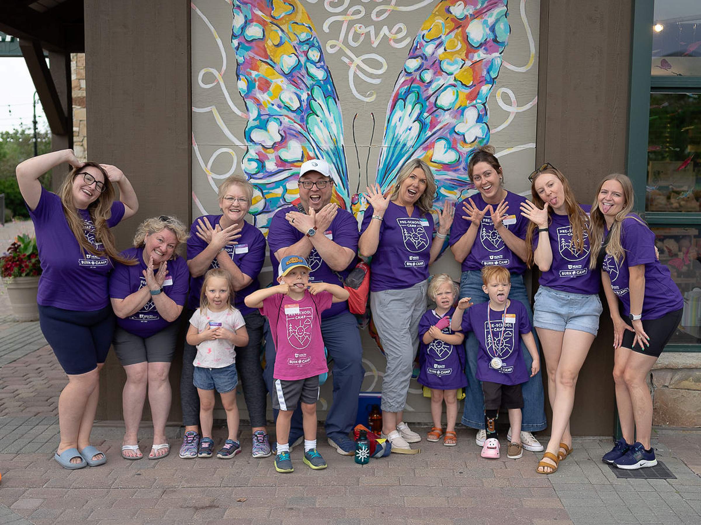 Group of burn camp attendees pose in front of a butterfly mural