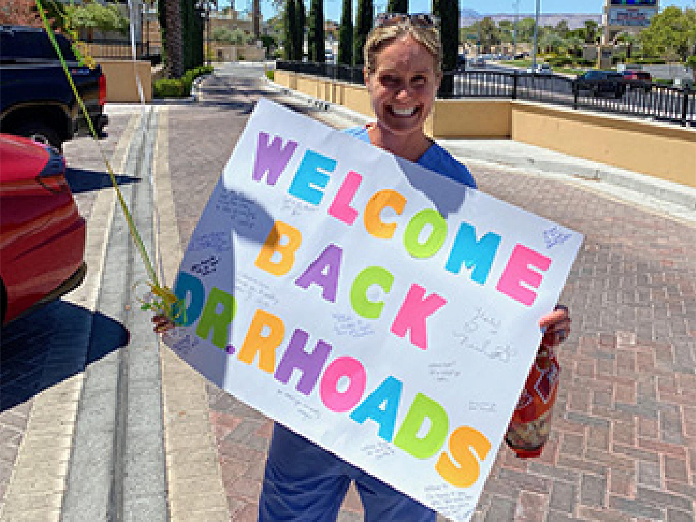 Rhoads Larkin, TBI patient, holding a welcome back sign