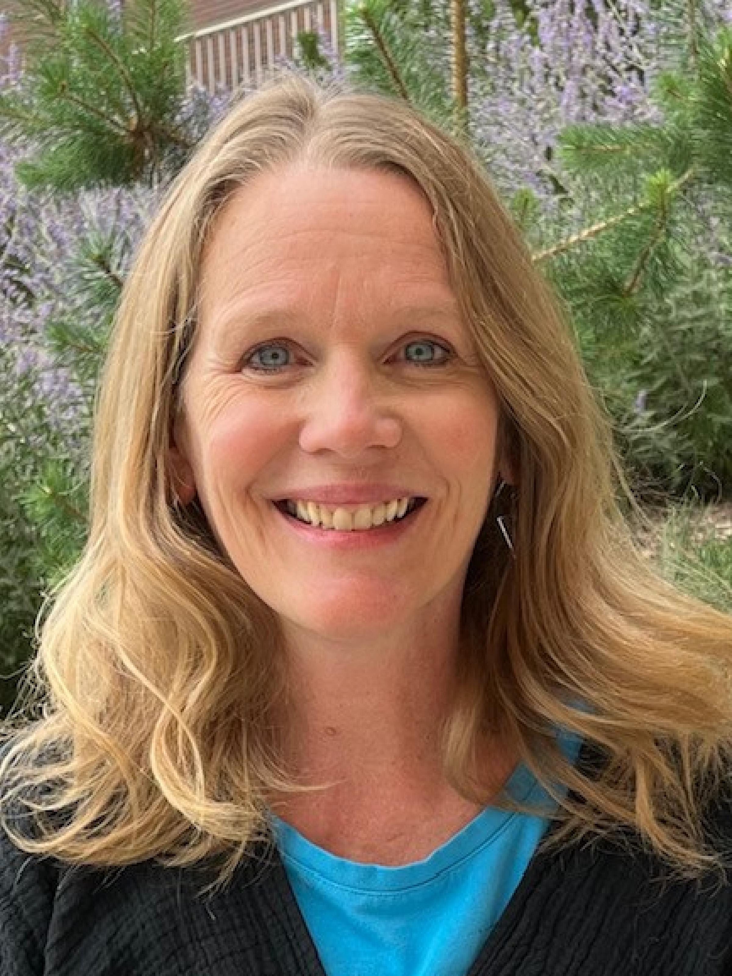 Woman with long blonde hair smiles in nature