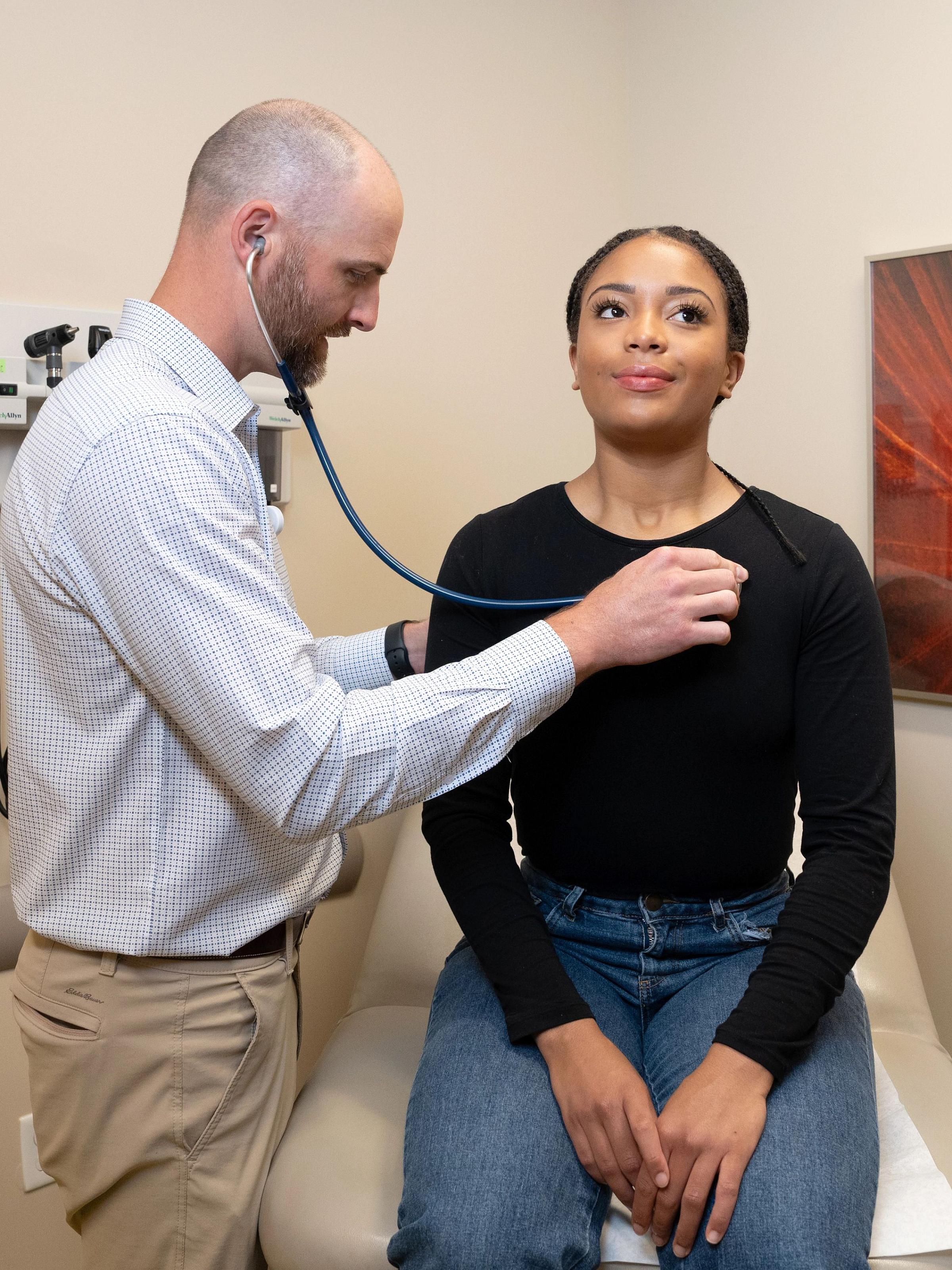Jedidiah Kowalski,FNP.APRN, listens to a female patient's heart