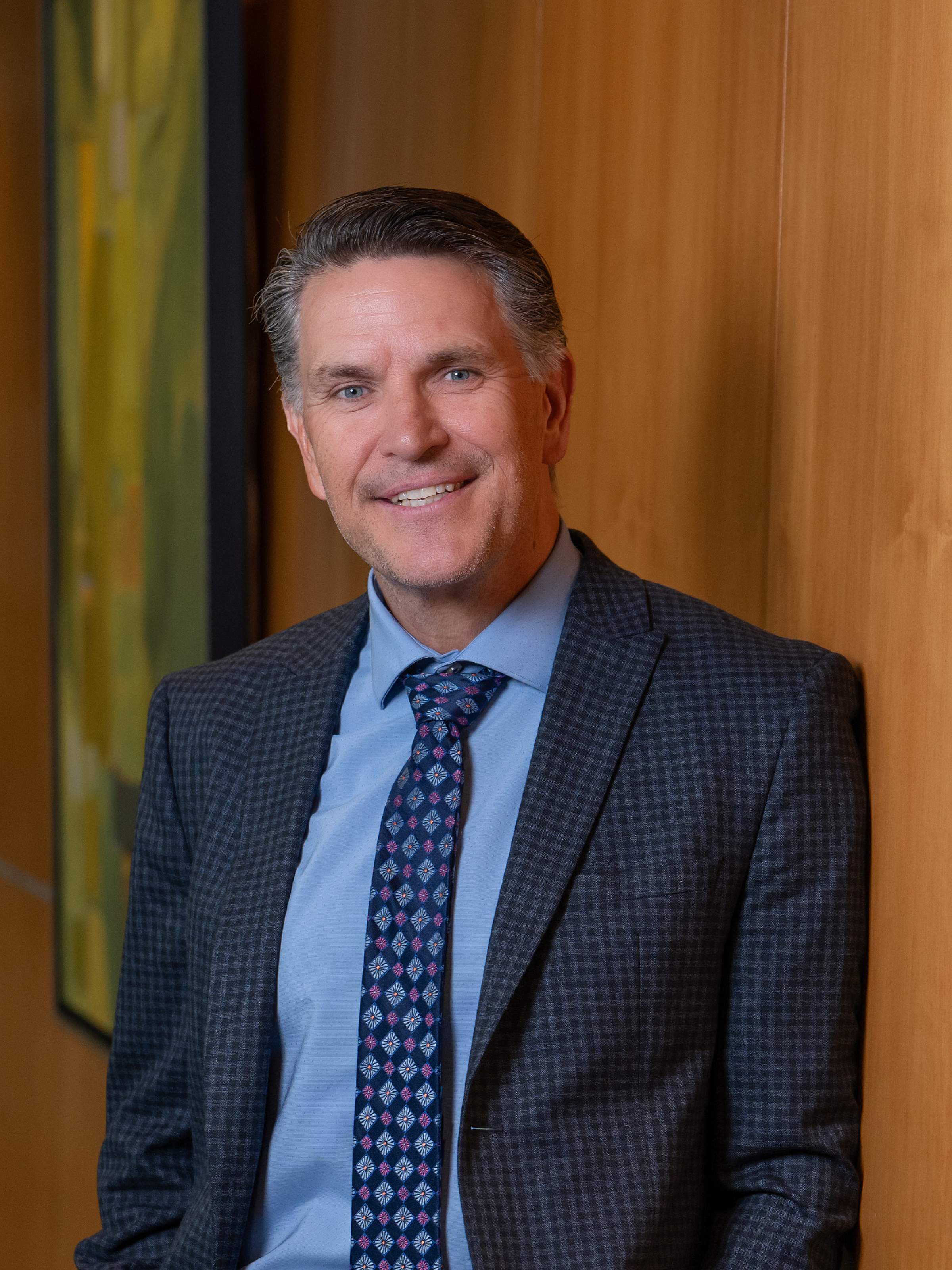 Dave Eldredge has silver hair and wears a dark gray pinstripe suit with a blue shirt and tie.