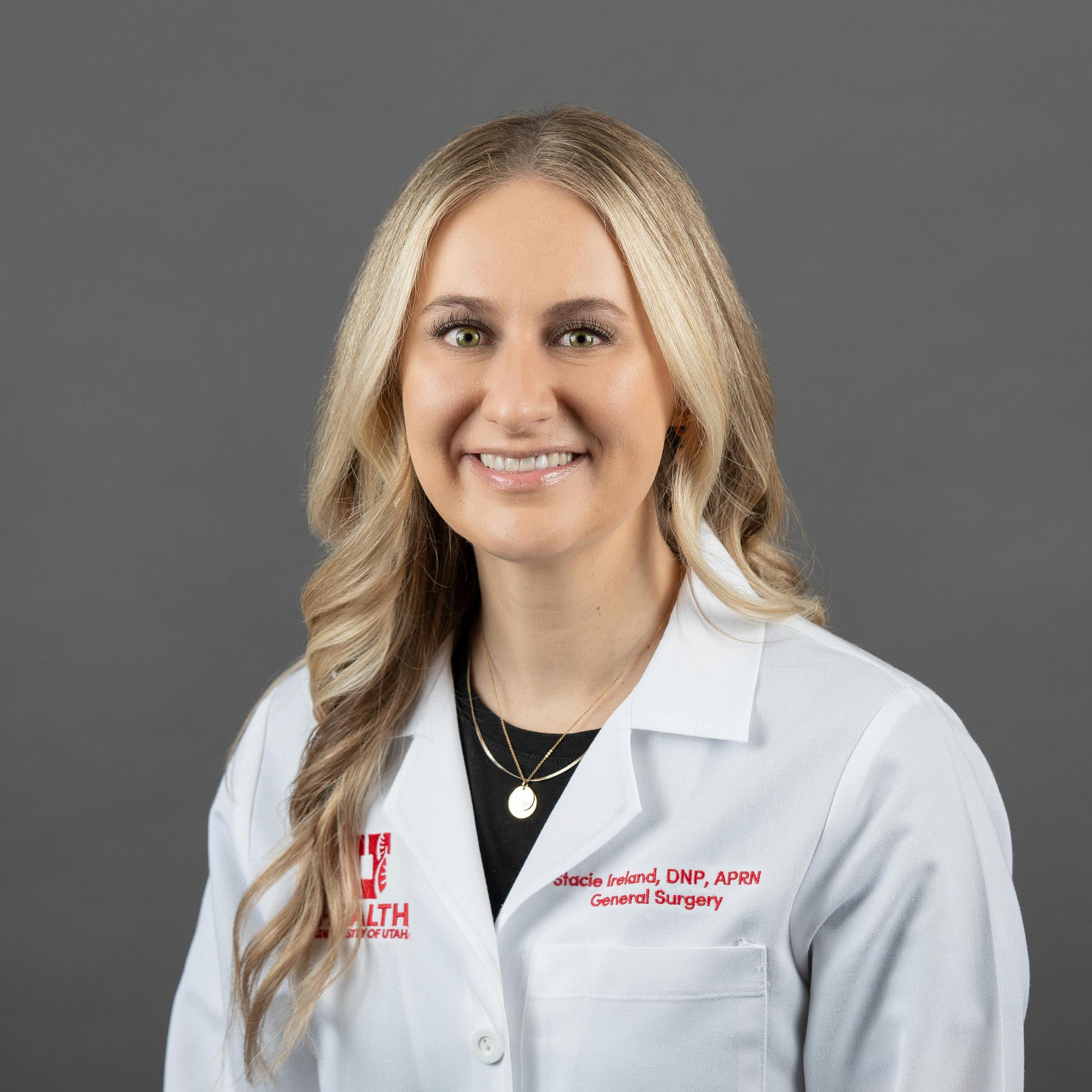 Stacie Ireland, a light-skinned woman with long blonde hair, wears a white coat and smiles