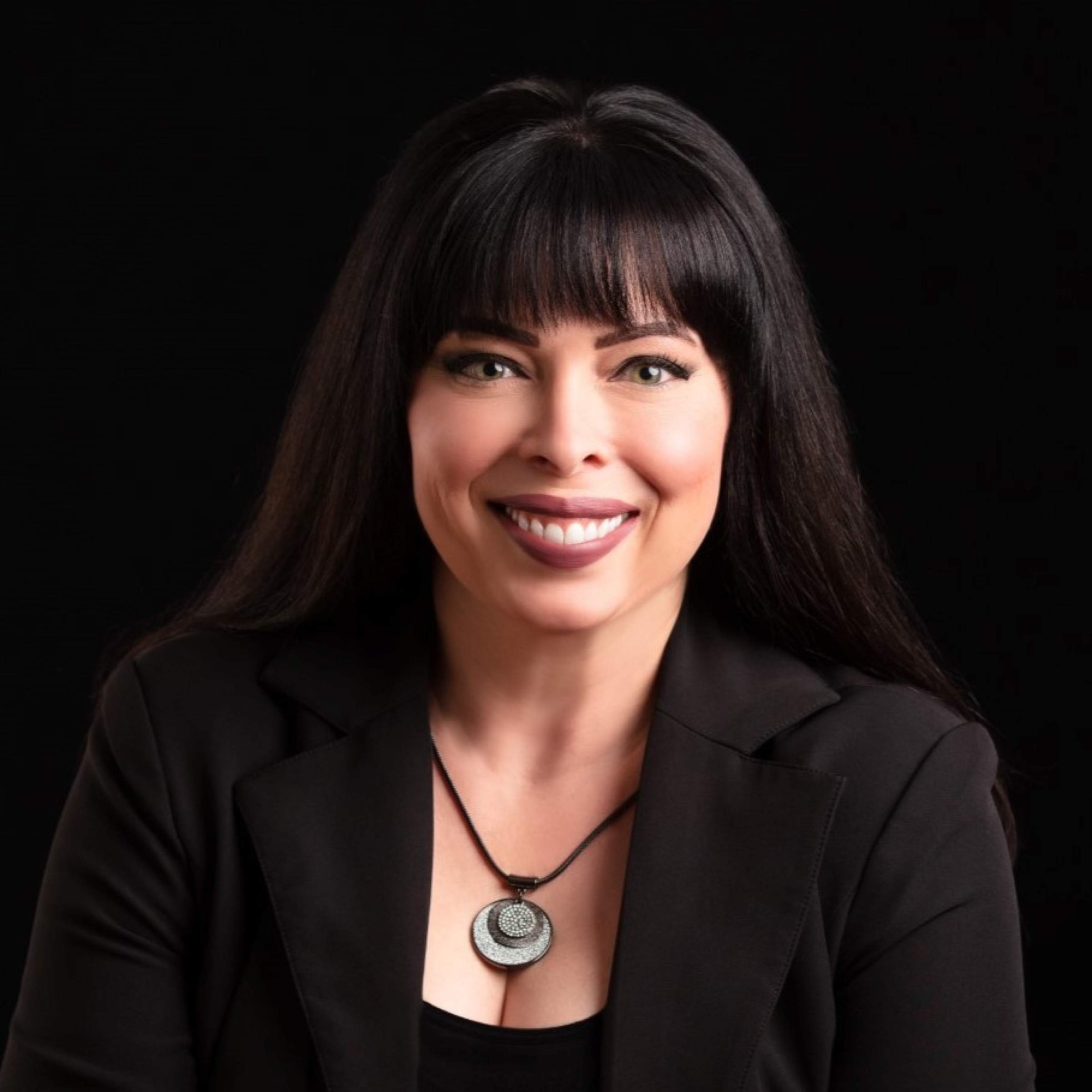 Headshot of woman with long black hair and bangs