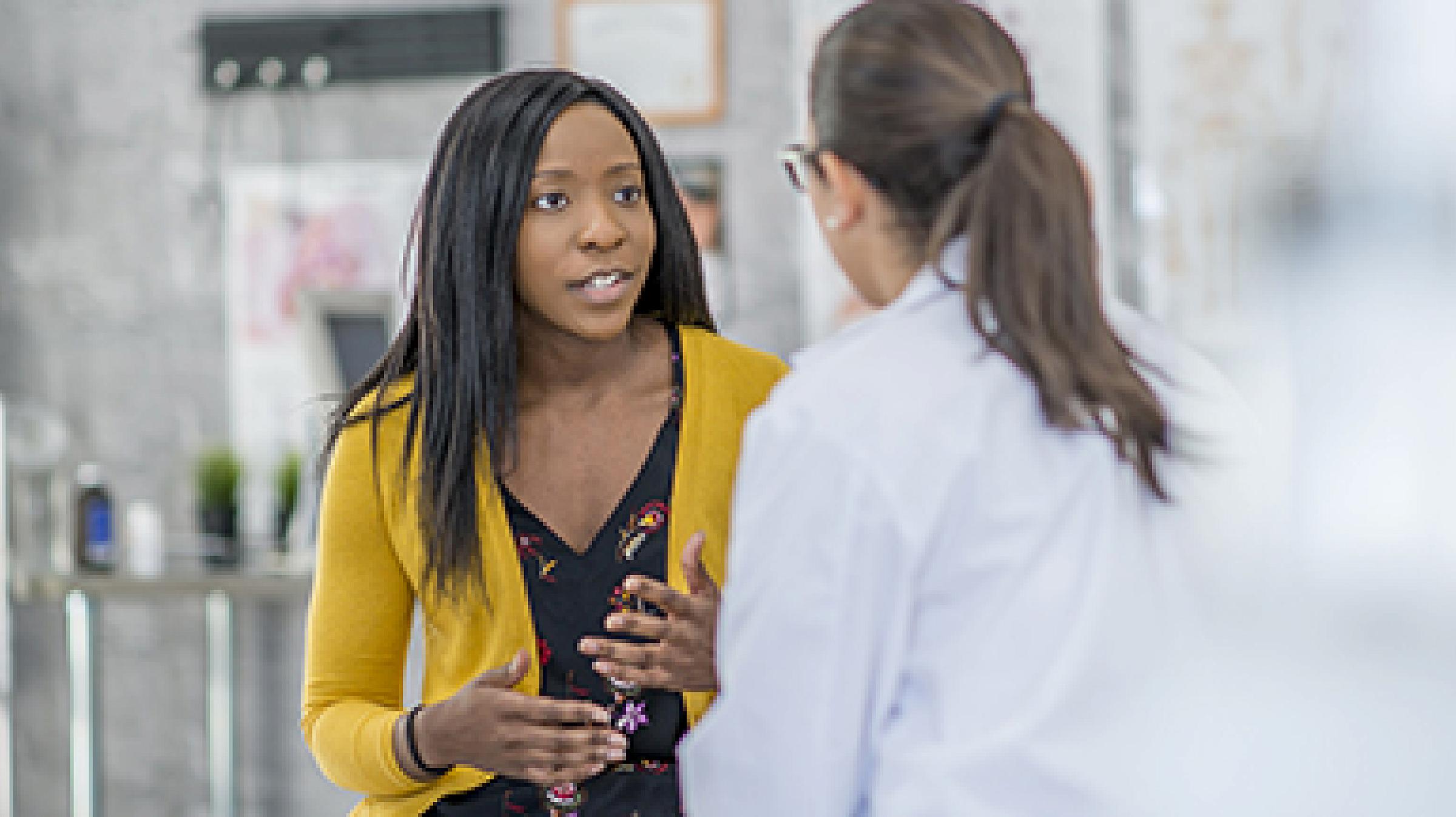 Woman in yellow sweater talking to a doctor