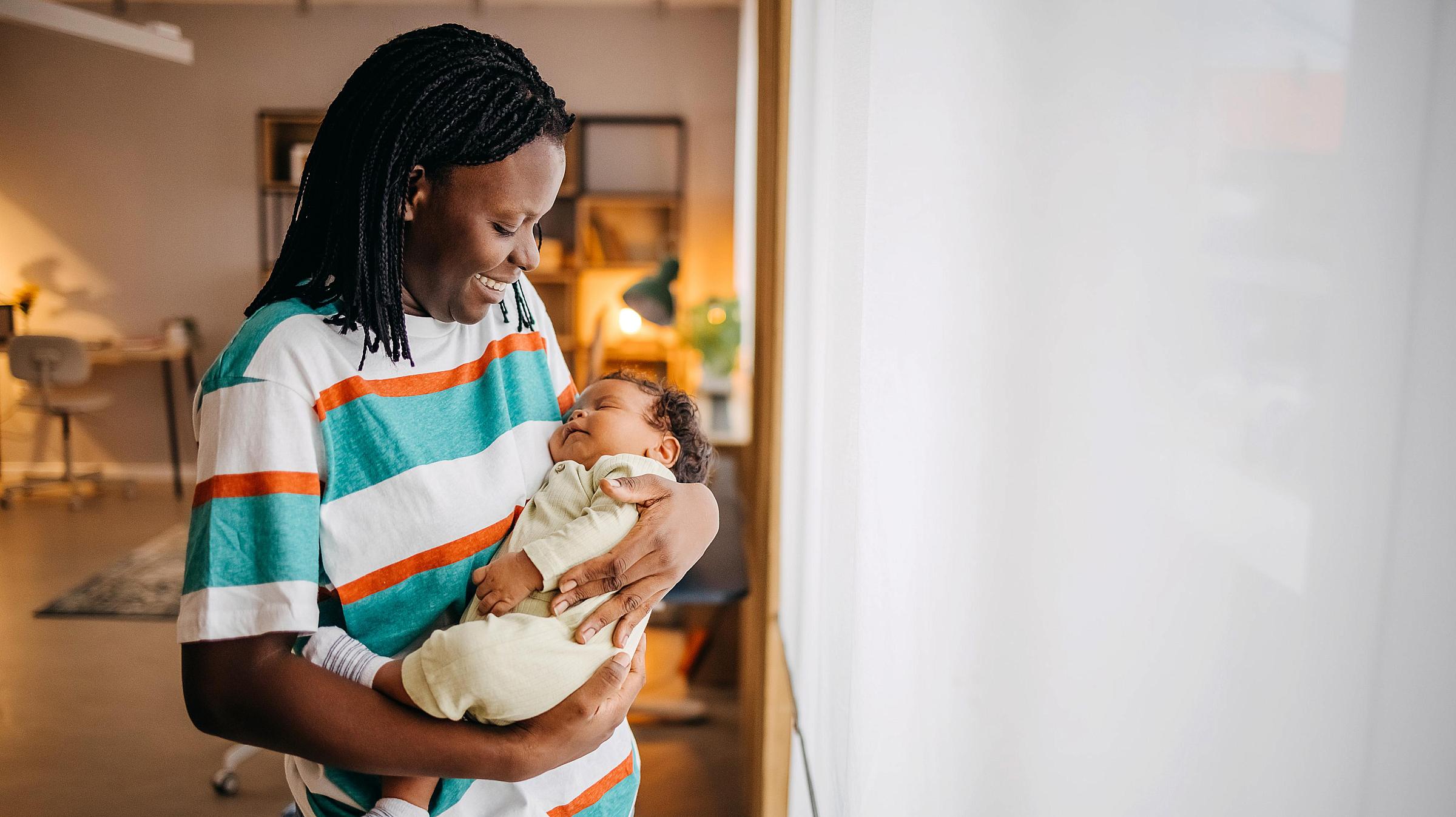 Mother with dark skin and braids holds newborn baby