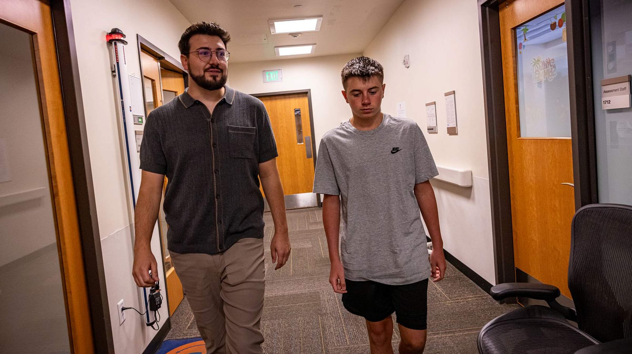 Staff member and youth walking through a hallway at Huntsman Mental Health Institute's Youth Crisis Care center.